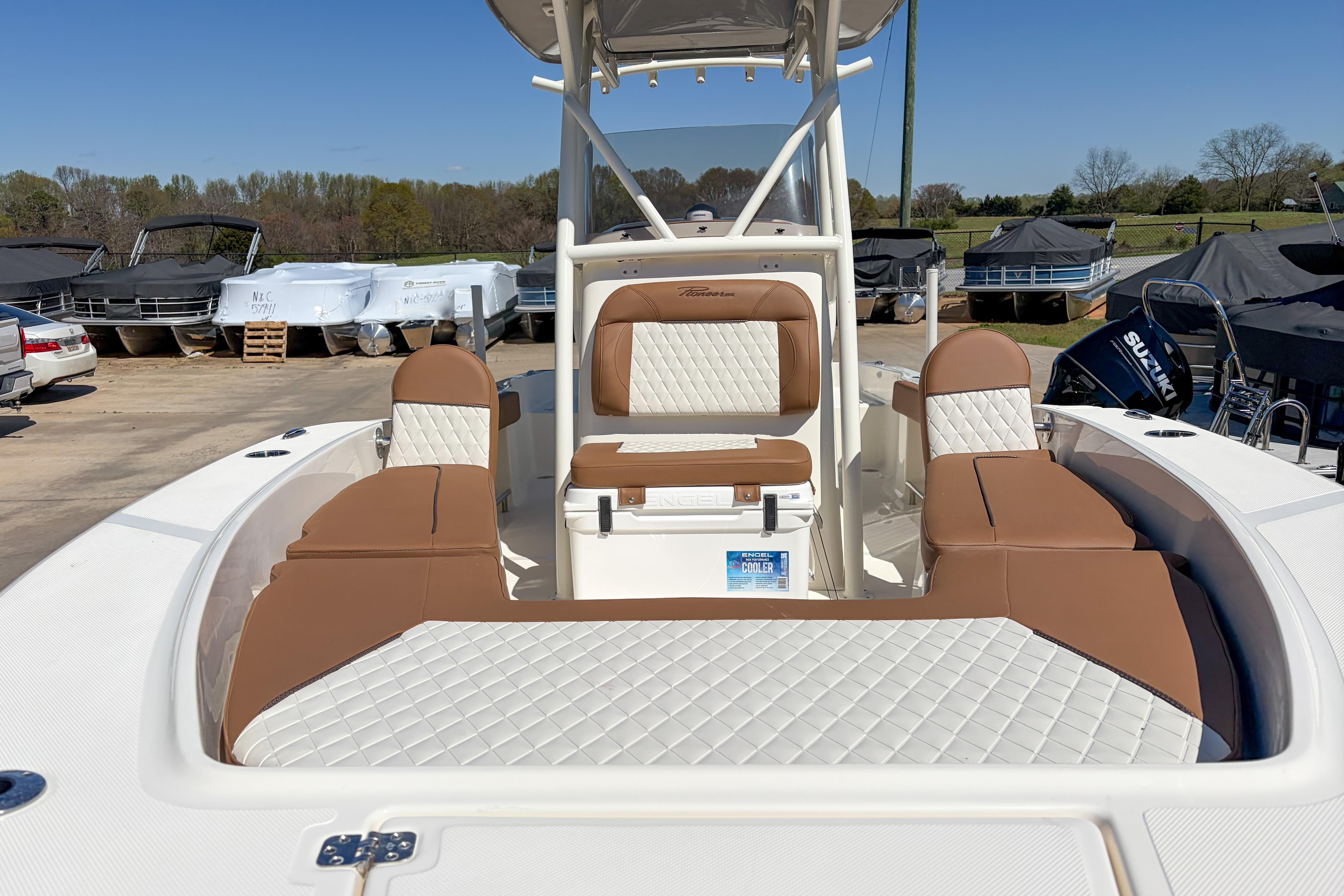 2026 Pioneer 220 Bay Sport boat with tan and white seating, parked outdoors.