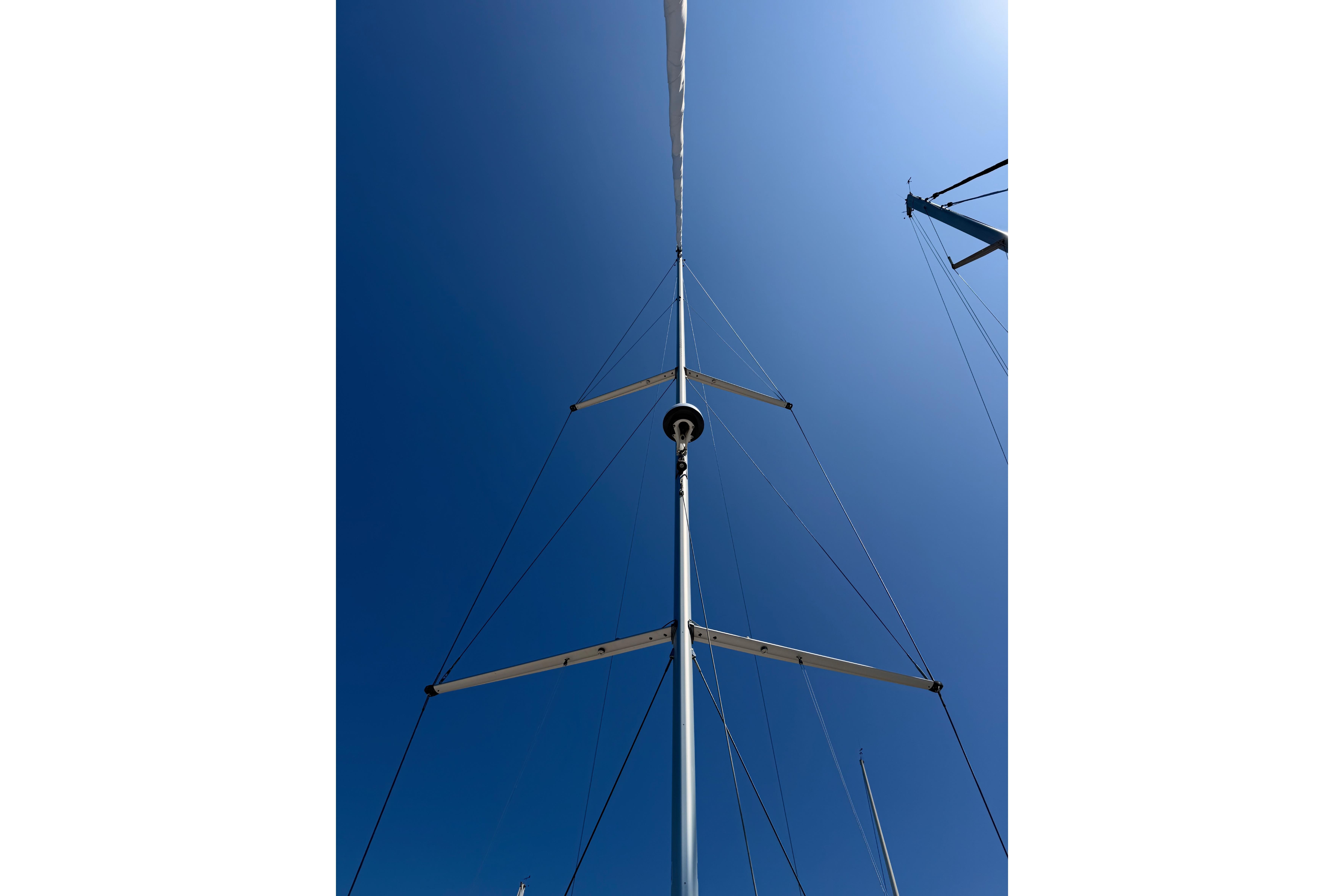 Mast of 2022 Beneteau Oceanis Yacht 54 against clear blue sky.