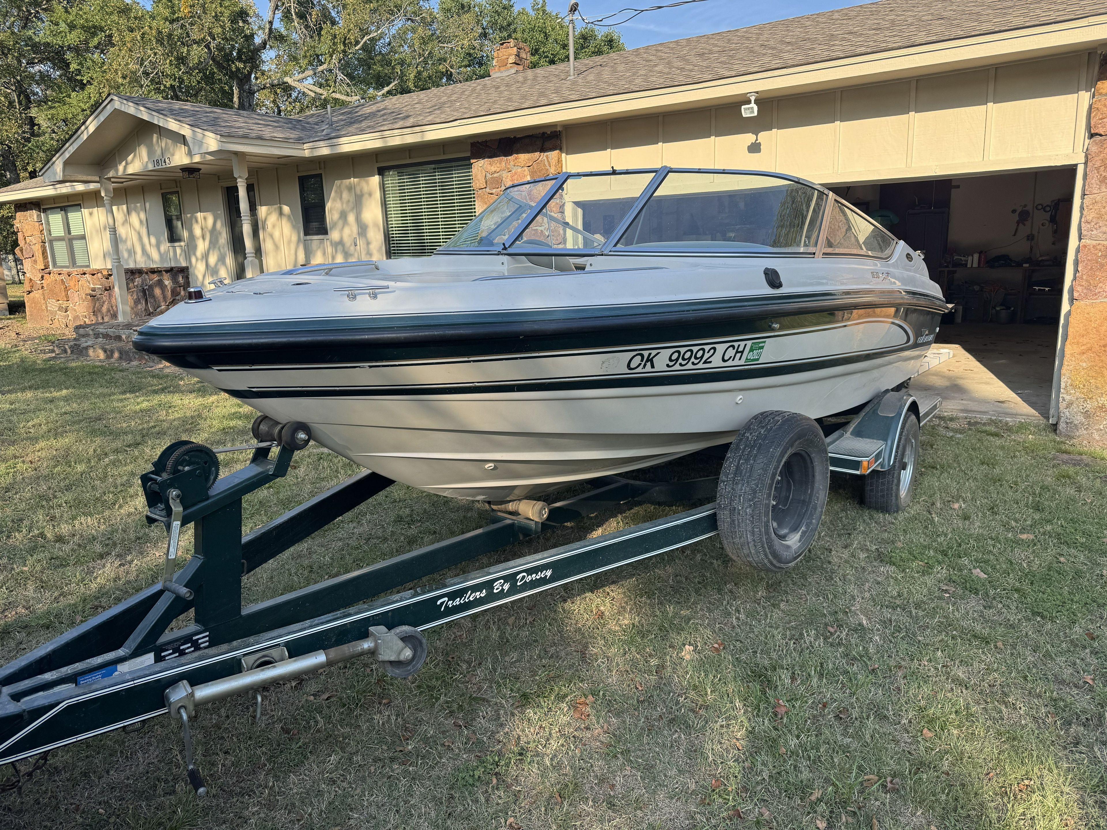 A 1996 Chaparral 1830 SS boat on a trailer in front of a house.
