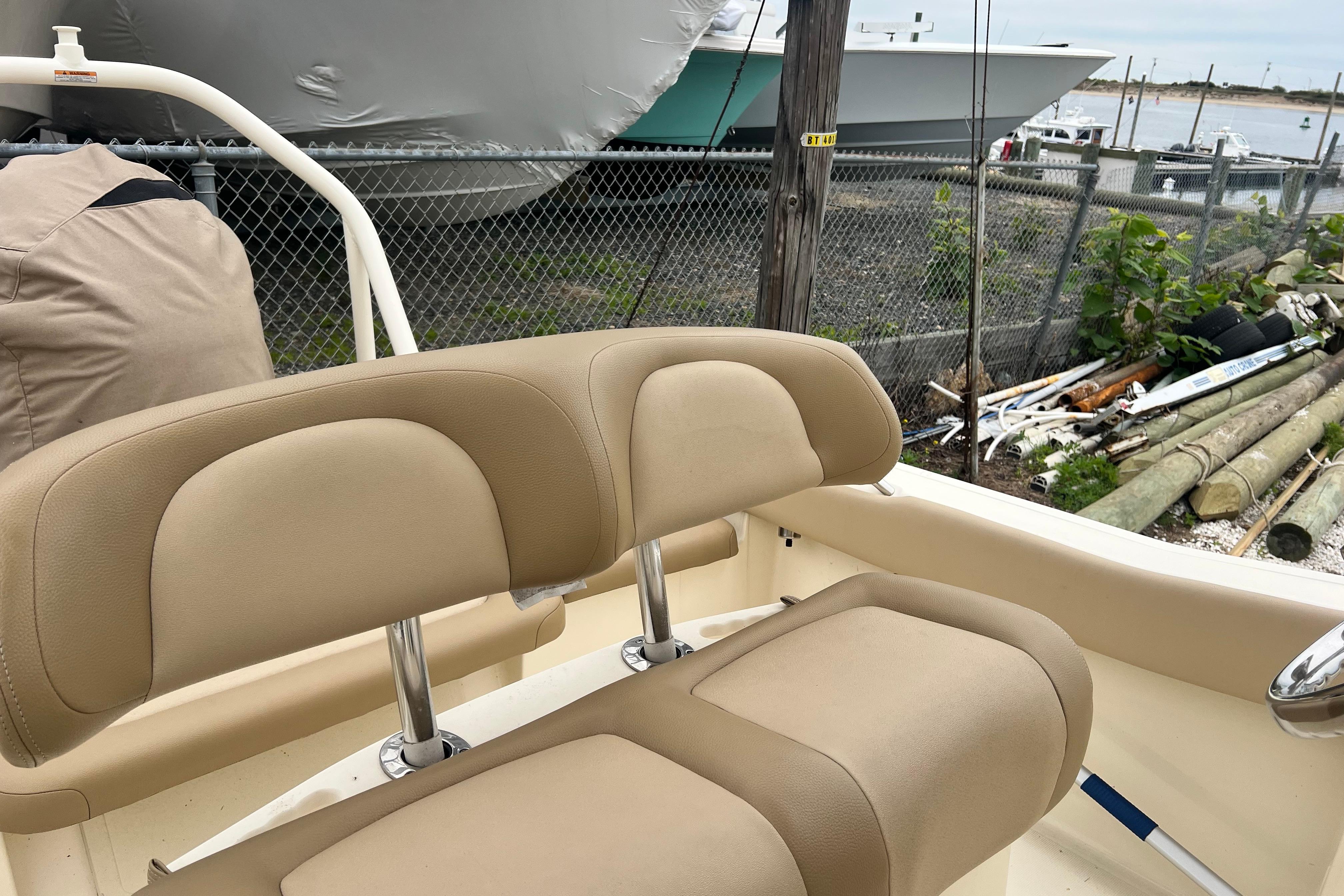 2020 Scout 195 Sportfish boat with beige seating, docked near a fence.
