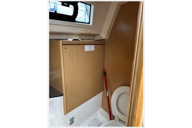 Bathroom interior of 2017 Bavaria 34 Cruiser yacht, featuring wooden cabinetry and a compact toilet.