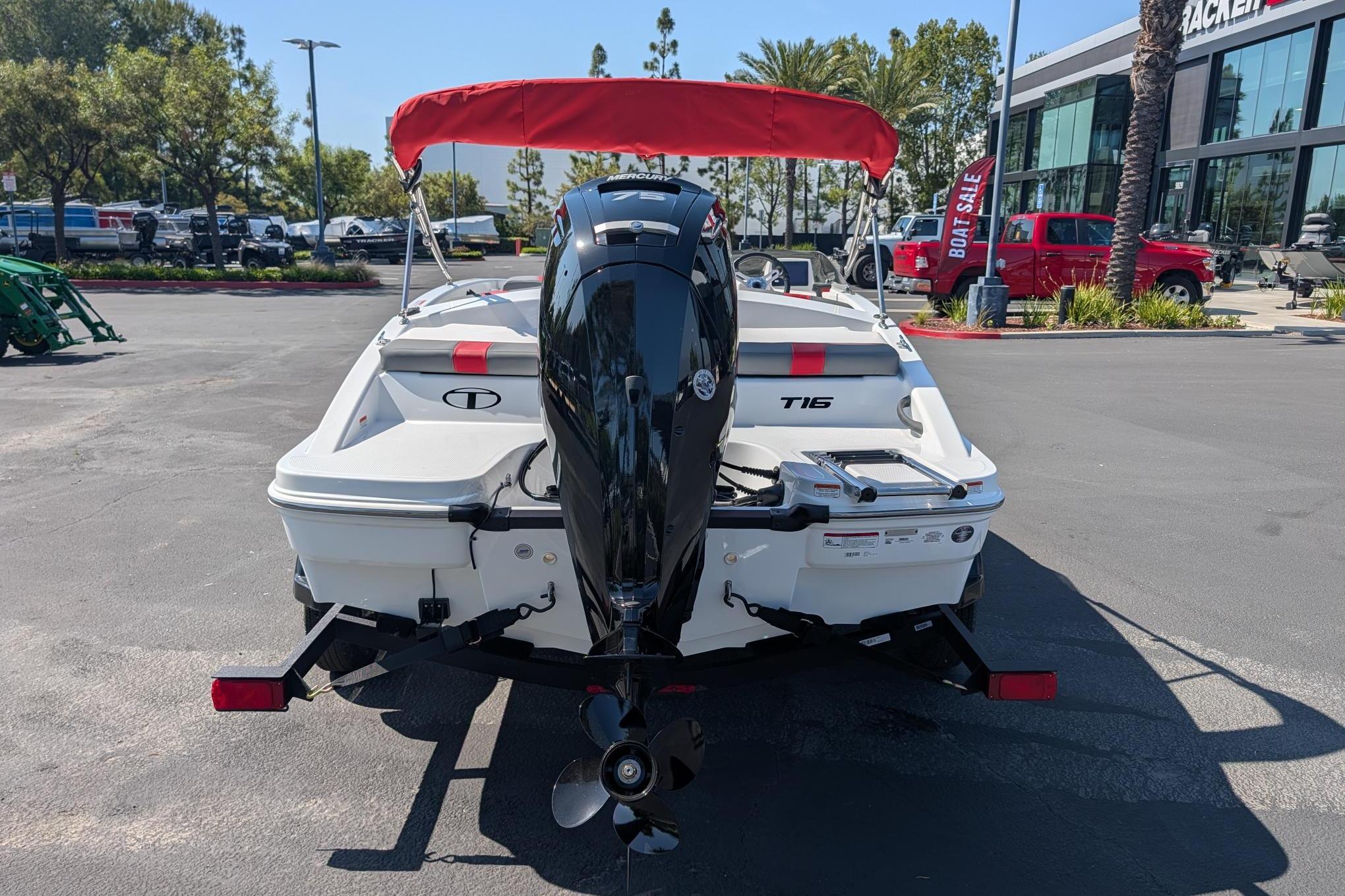2026 Tahoe T16 boat with red canopy, parked outdoors near dealership.