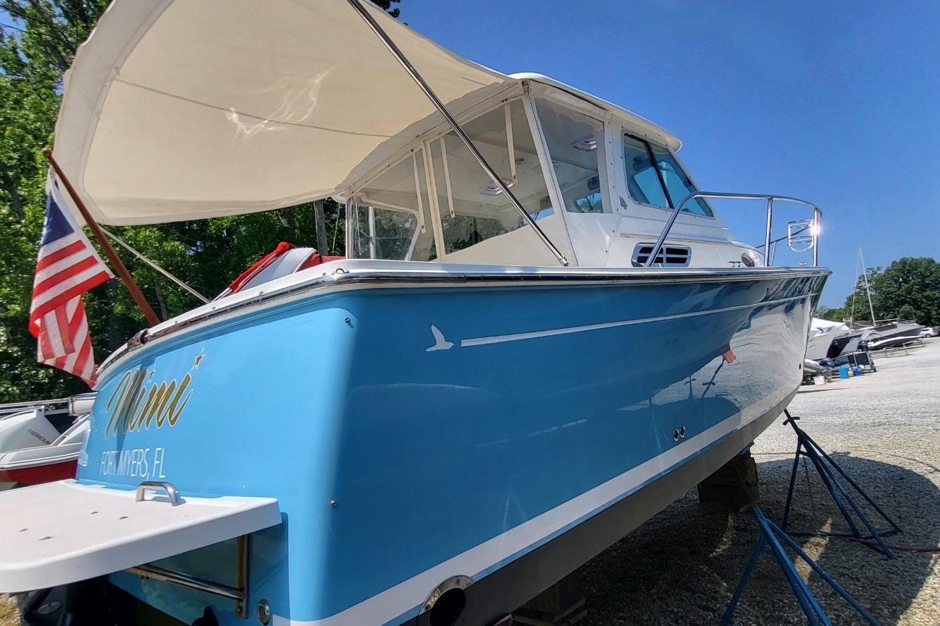 2006 Back Cove 29 boat with blue hull, docked outdoors under clear sky.