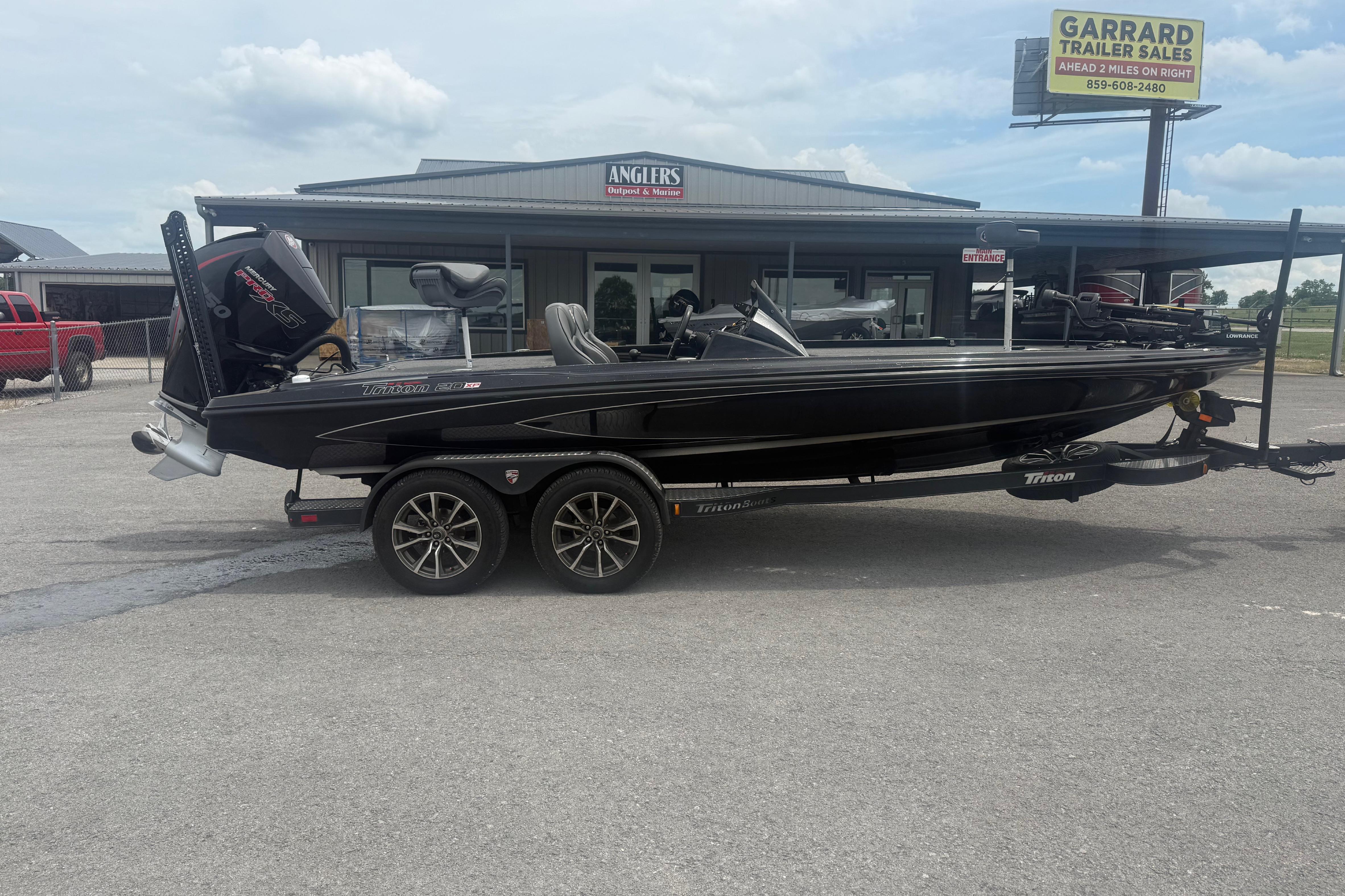 2024 Triton 20XP boat on trailer, parked outside dealership under cloudy sky.