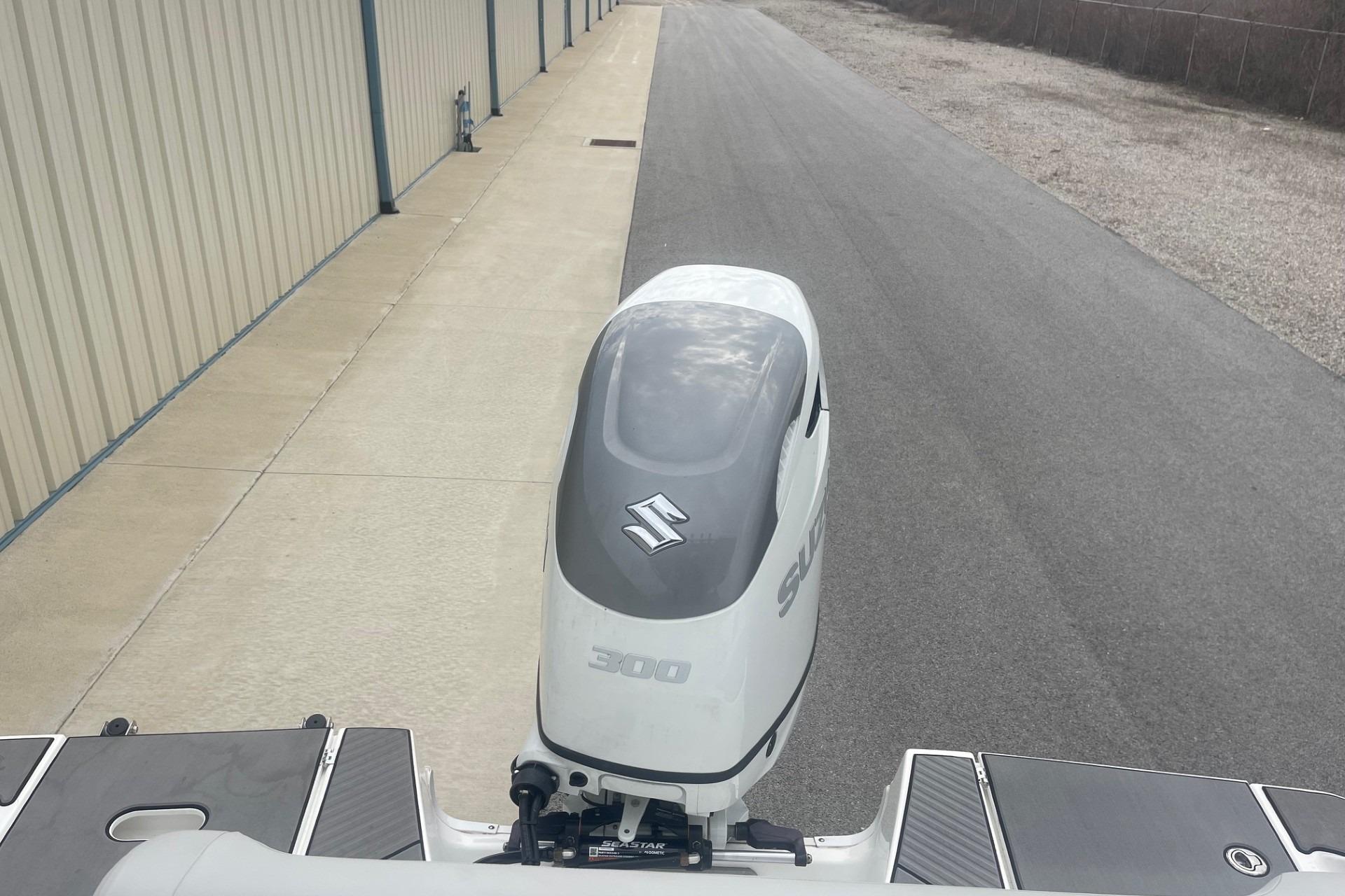 2025 Hurricane Center Console 24 OB with Suzuki 300 outboard motor, parked near a building.