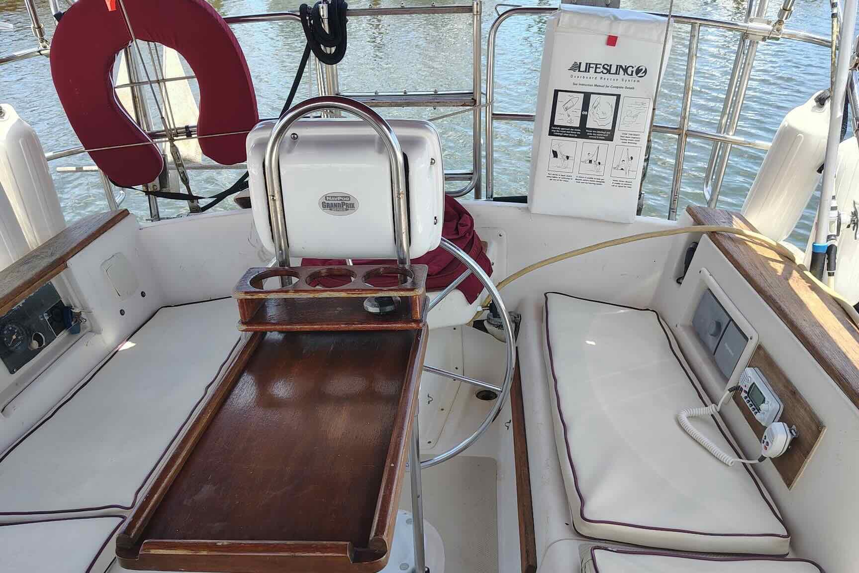 Cockpit of 1989 Island Packet 35 sailboat with seating, steering wheel, and lifesaving equipment.