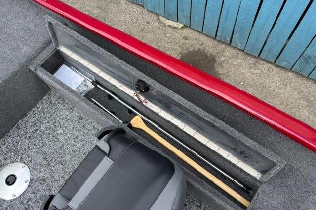 Storage compartment in 2025 Tracker Super Guide V-16 SC boat with fishing gear and paddle.