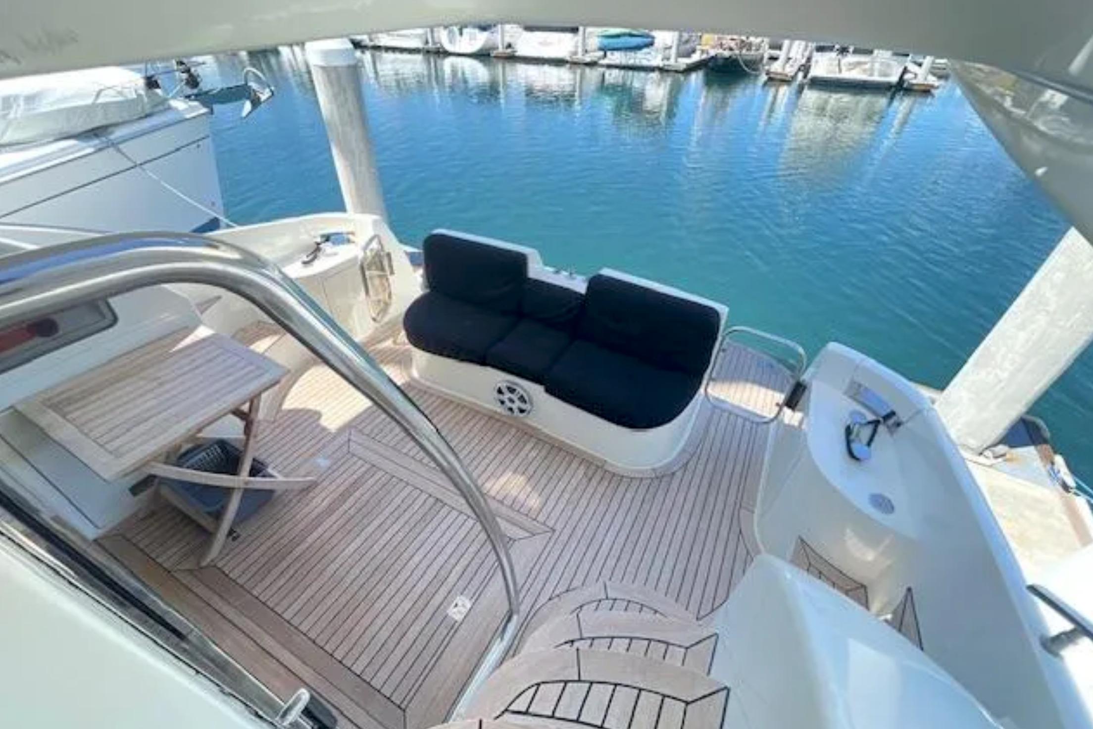 2004 Azimut 46 yacht deck with seating and table, overlooking marina waters.