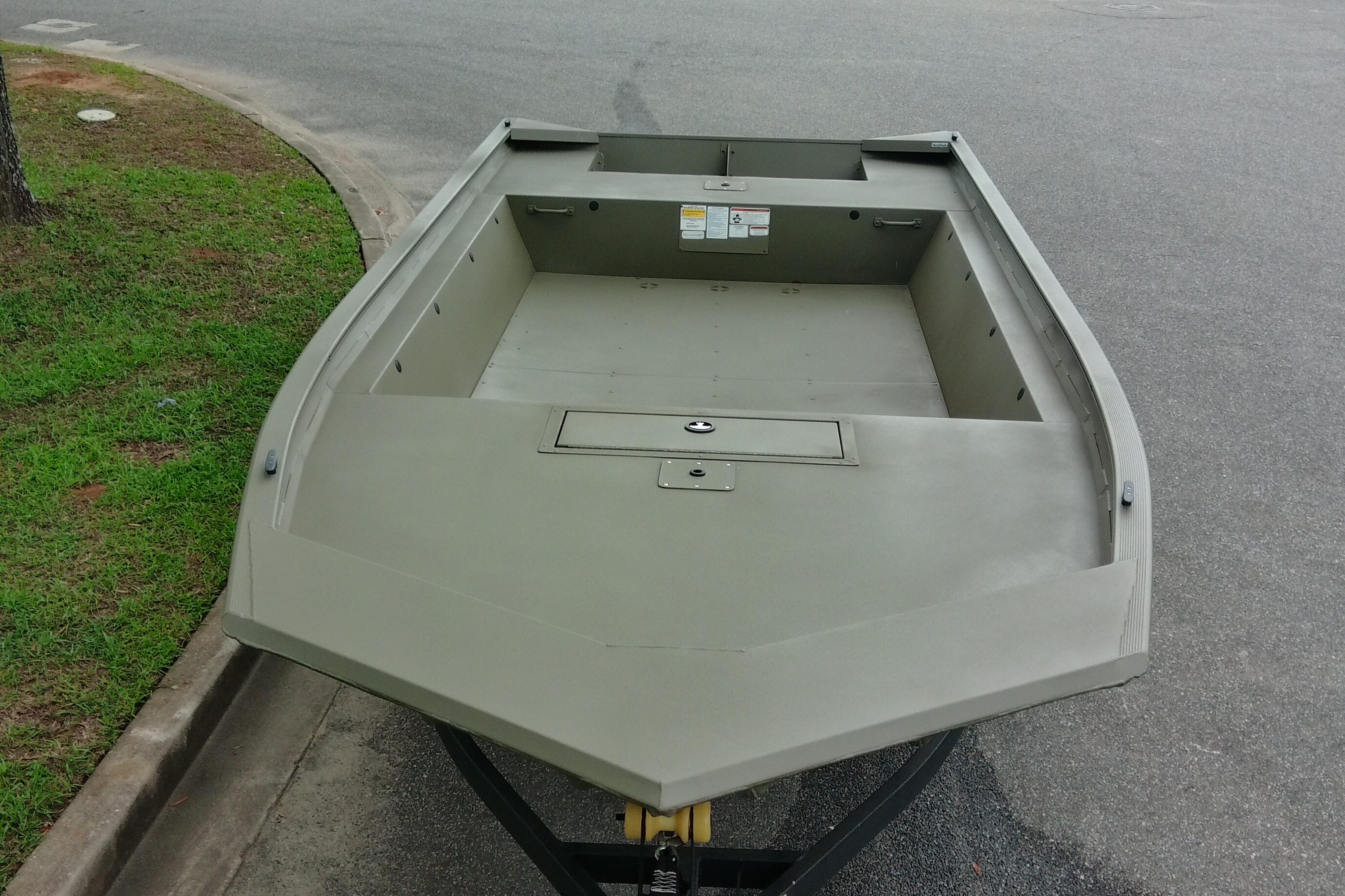 2026 Tracker Grizzly 1860 Utility boat on trailer, parked on asphalt near grass.