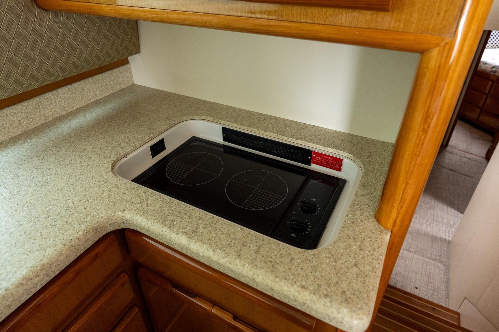 Compact kitchen stove in 2000 Viking 50' Convertible yacht, featuring sleek countertop design.