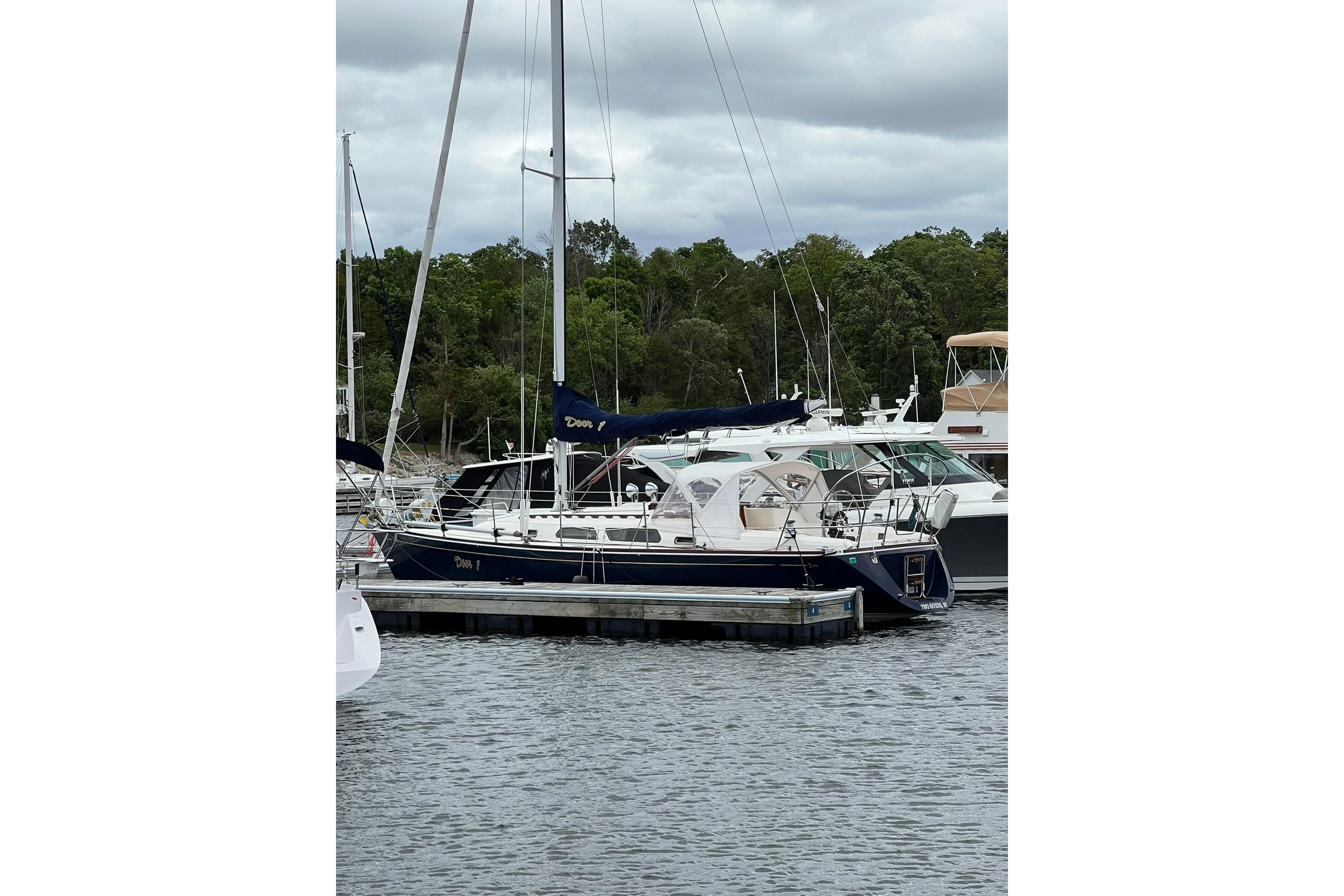 1998 Sabre 362 sailboat docked at marina, surrounded by lush greenery and calm waters.