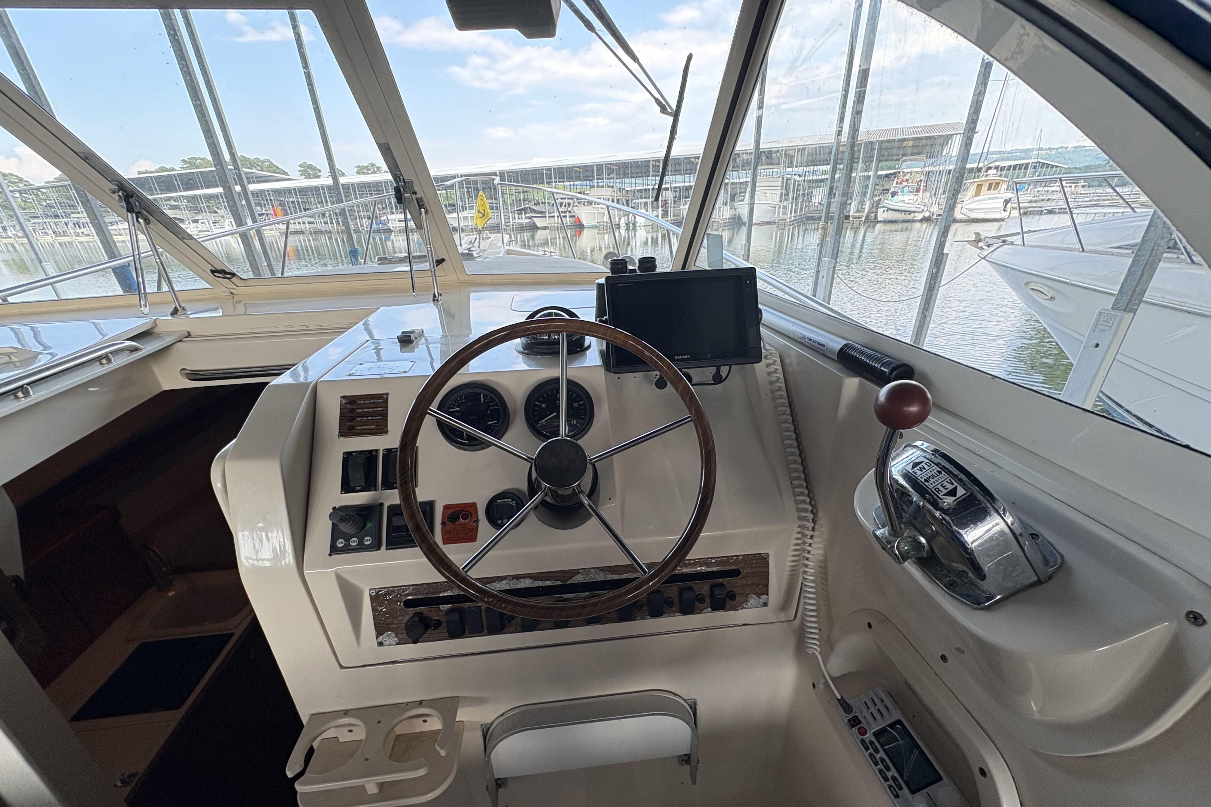 2003 Mainship Pilot 30-II helm with steering wheel, controls, and marina view.