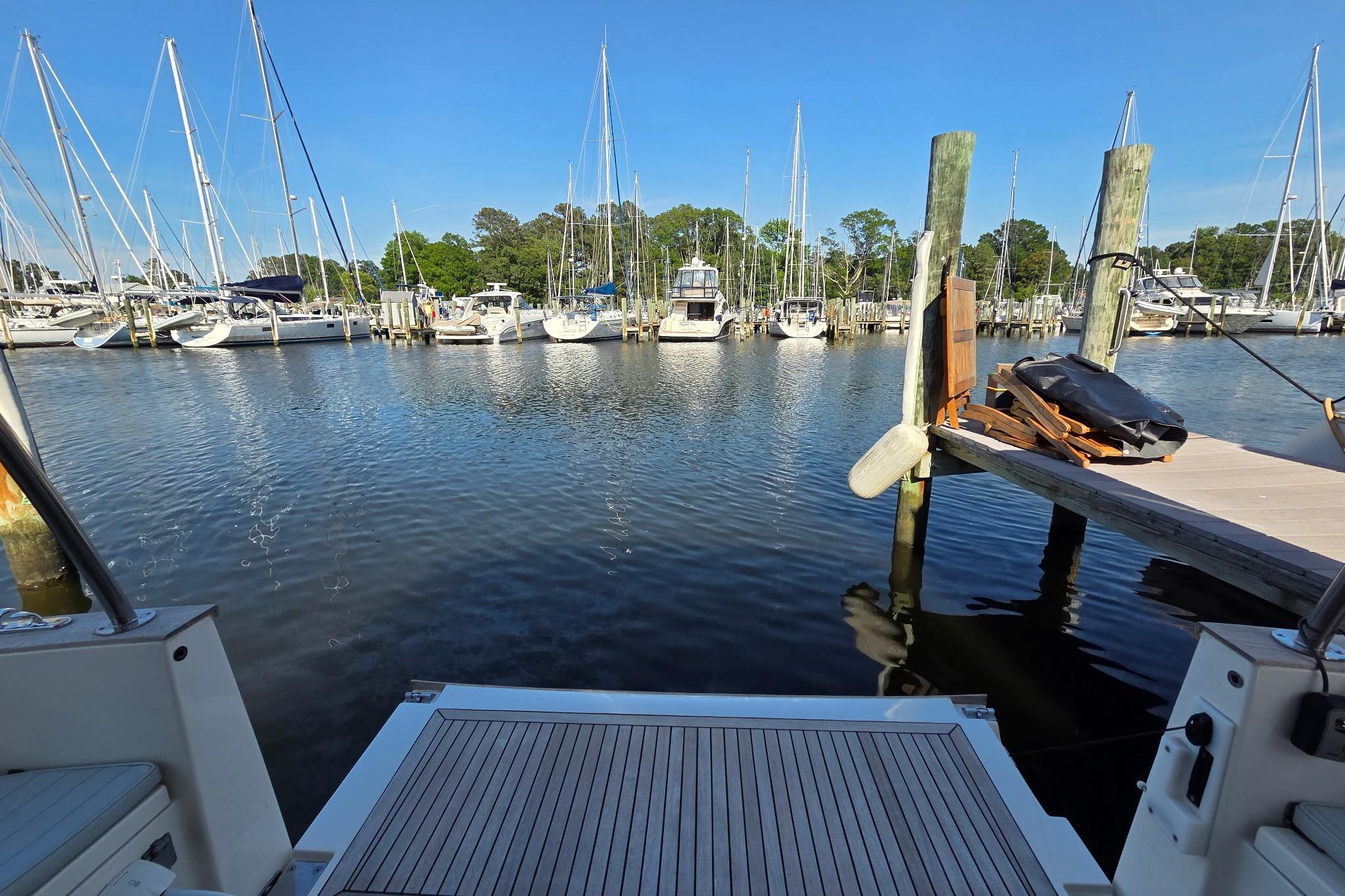 Marina view from a 2023 Greenline 40 yacht, showcasing sailboats and clear blue skies.