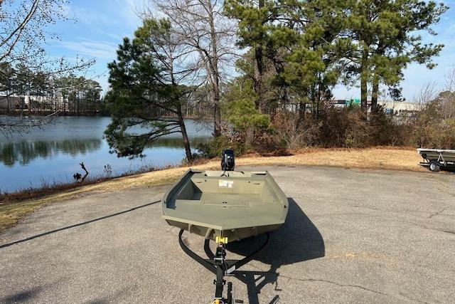 2026 Tracker Grizzly 1860 Utility boat on trailer by a scenic lake.
