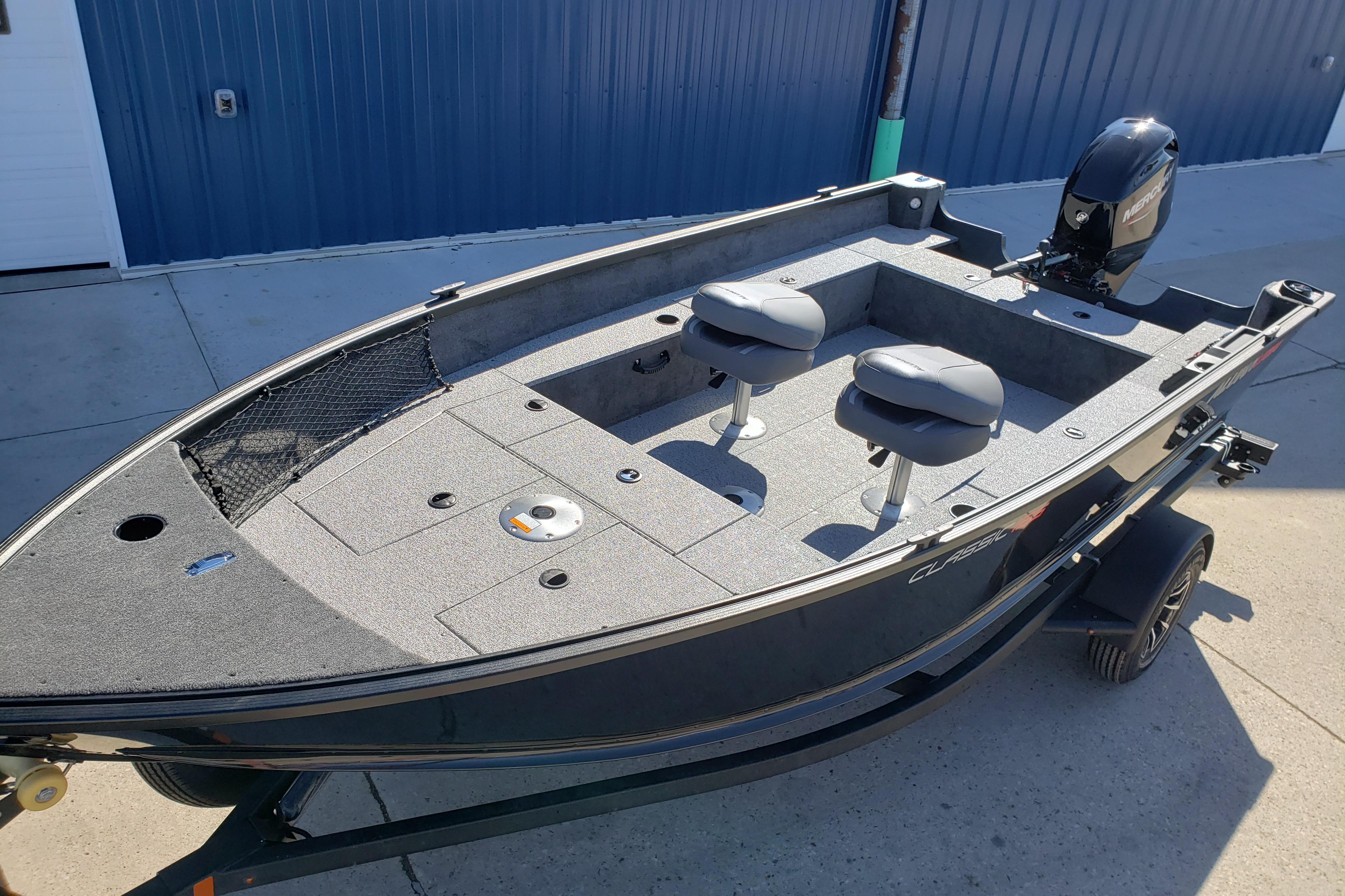 2026 Alumacraft Classic 165 Tiller boat with dual seats and motor, parked outdoors.