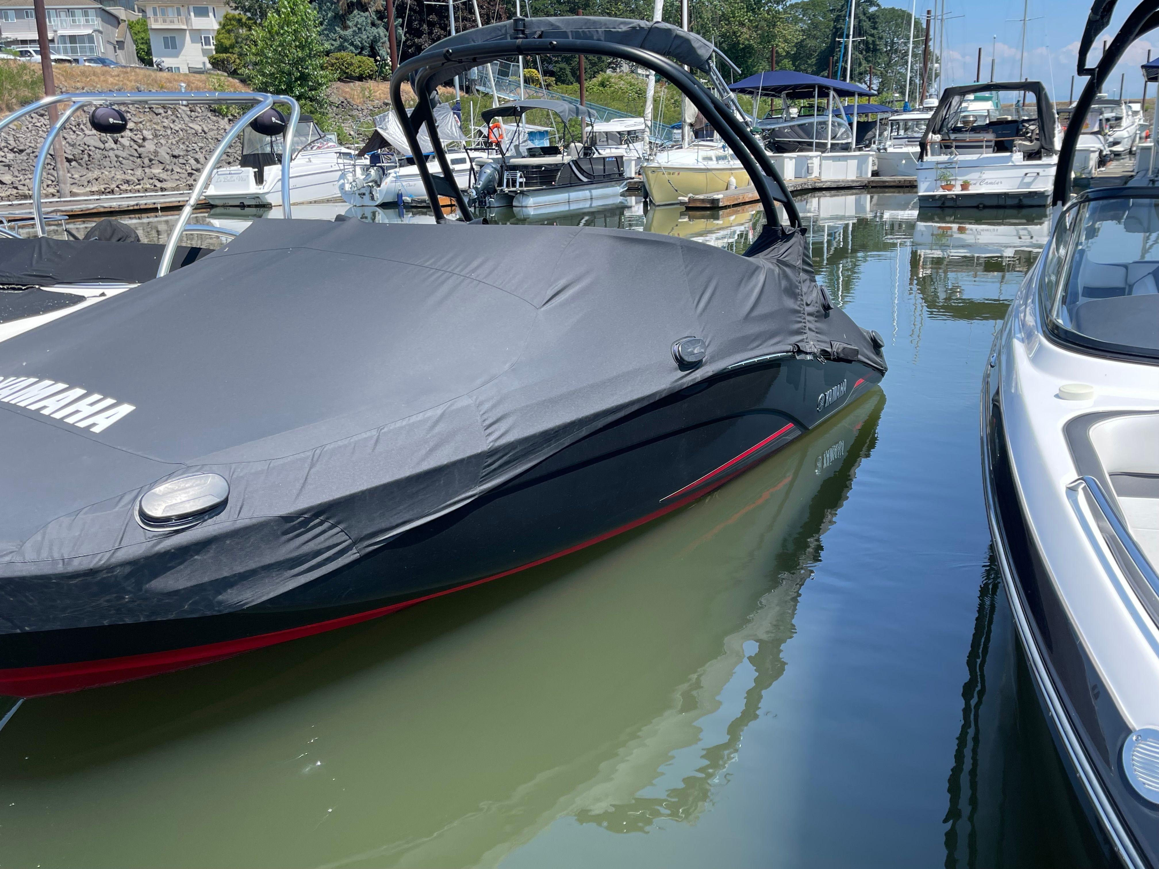 A 2018 Yamaha 212 Limited S boat is in the water, covered with a protective cover.