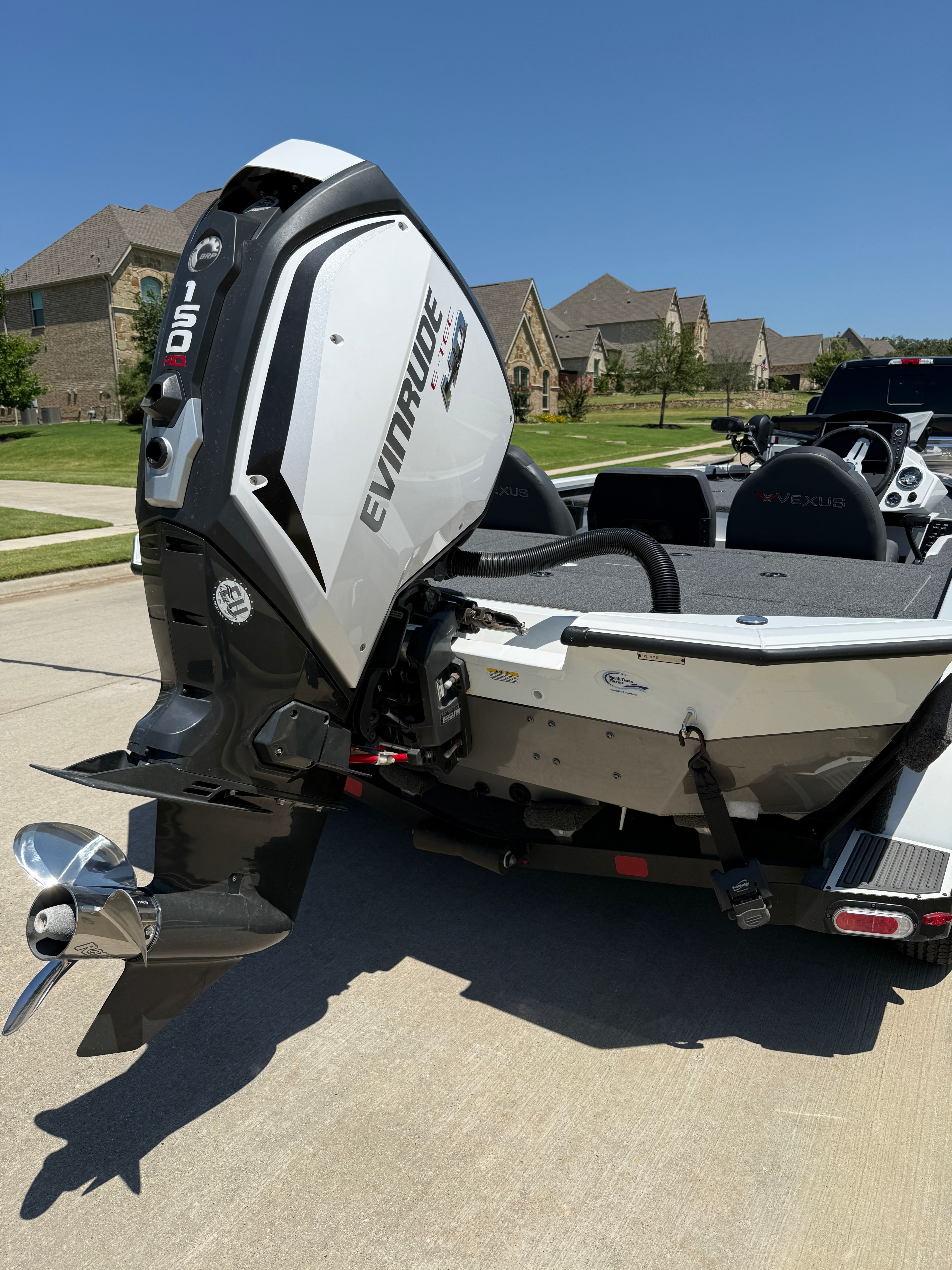 A 2019 Vexus AVX1980 boat with an Evinrude outboard motor, parked in a residential area.