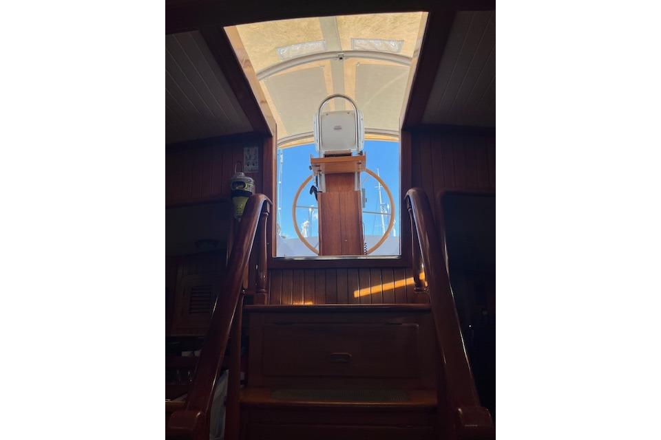 Interior view of 1986 Liberty 49 yacht, showcasing wooden stairs and helm station.