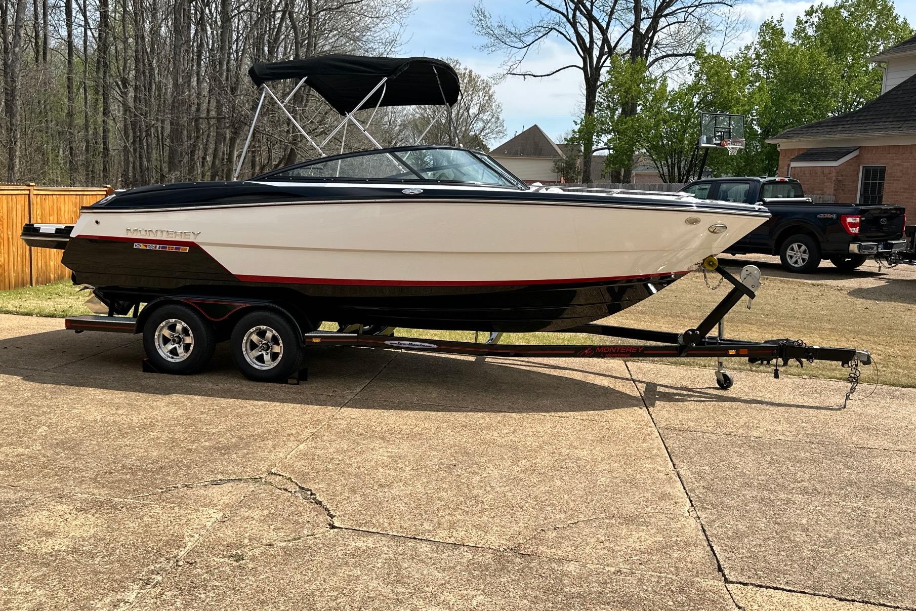 2016 Monterey 238SS Super Sport boat on trailer in driveway, surrounded by trees and houses.