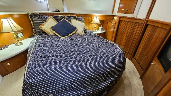 Luxurious bedroom interior of 2000 Carver 450 Voyager Pilothouse yacht with cozy bedding.