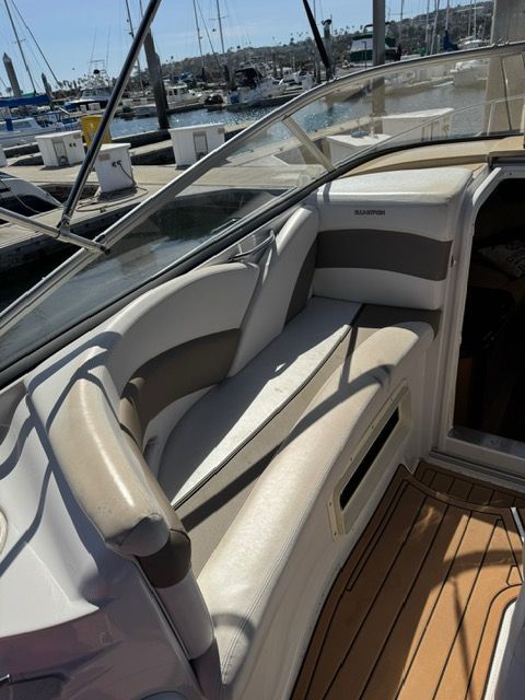 Interior view of a Glastron GS boat with beige seating area and wooden flooring.