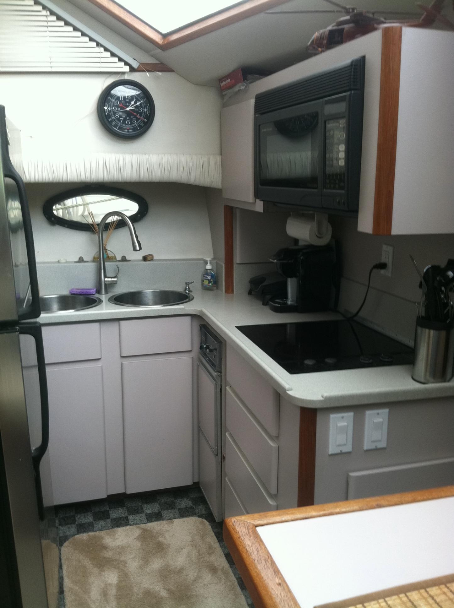 Compact kitchen in 1989 Californian 48 Motor Yacht with modern appliances and sink.