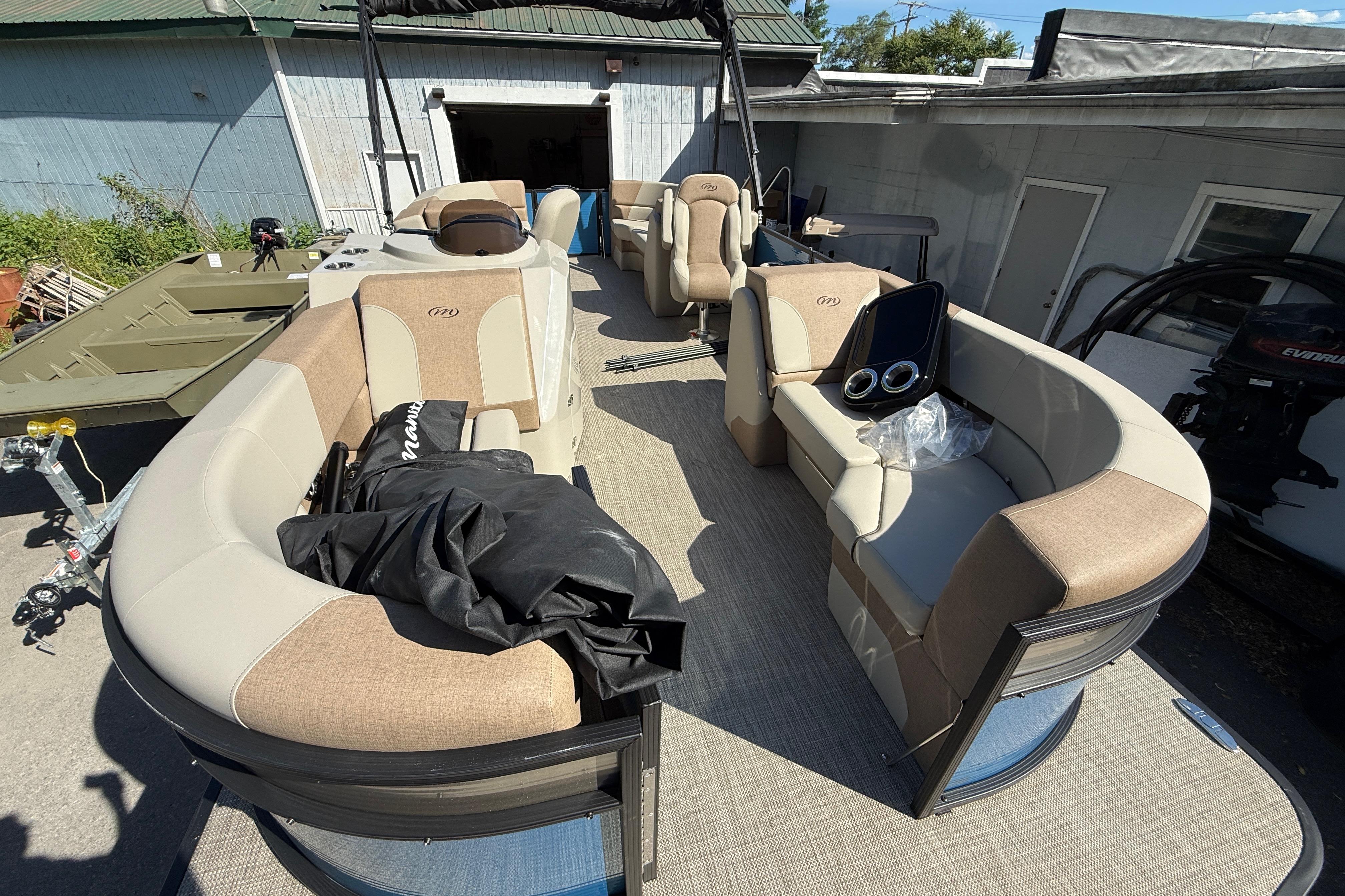 2027 Manitou Aurora RF 23 pontoon boat with beige seating and modern dashboard.