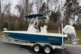 2026 Mako 24 APEX boat on trailer, blue hull, parked outdoors.