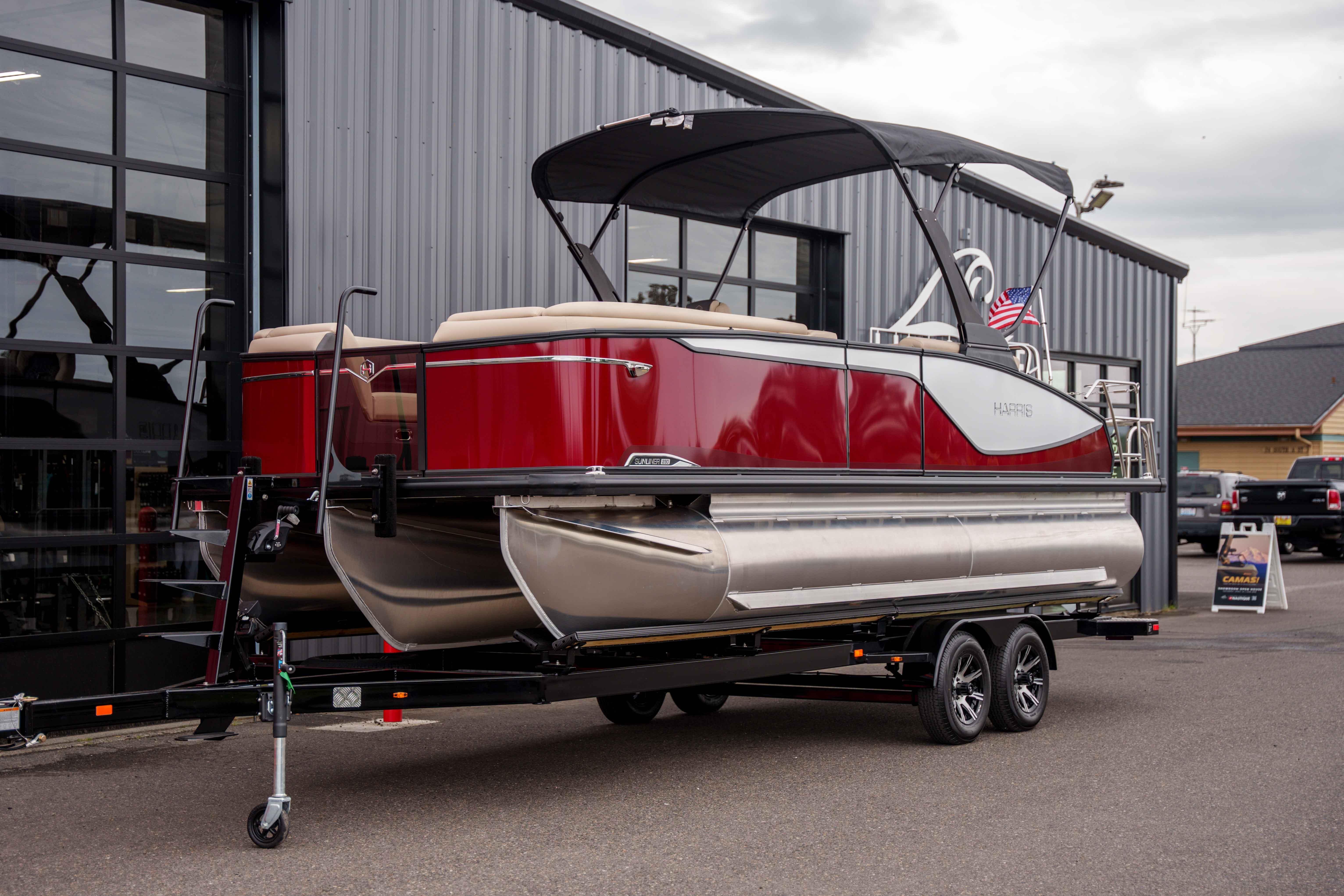 2026 Harris Sunliner 230 pontoon boat on trailer, parked outside a building.