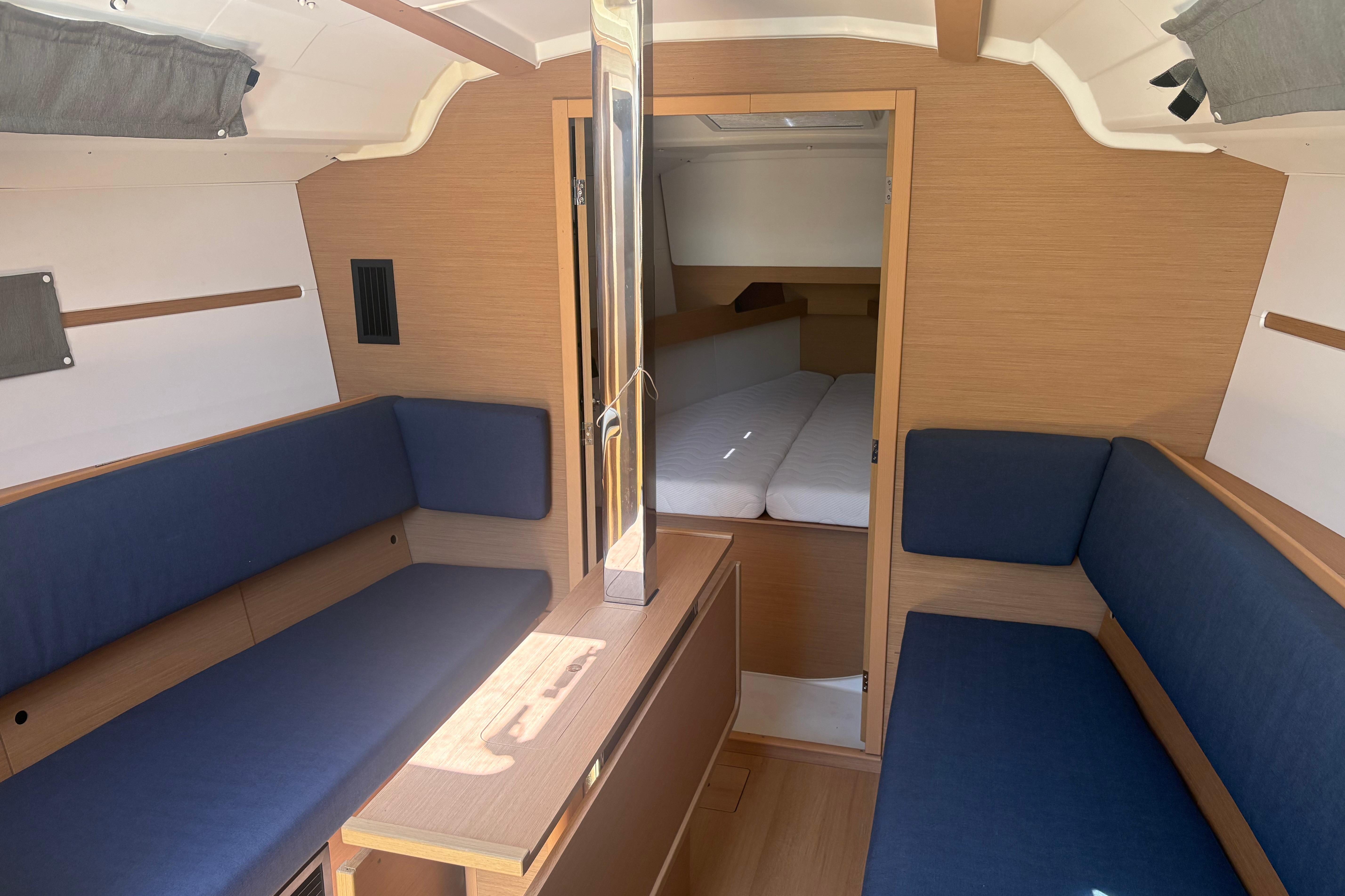 Interior of 2021 Jeanneau Sun Odyssey 349 sailboat with blue seating and wooden finishes.