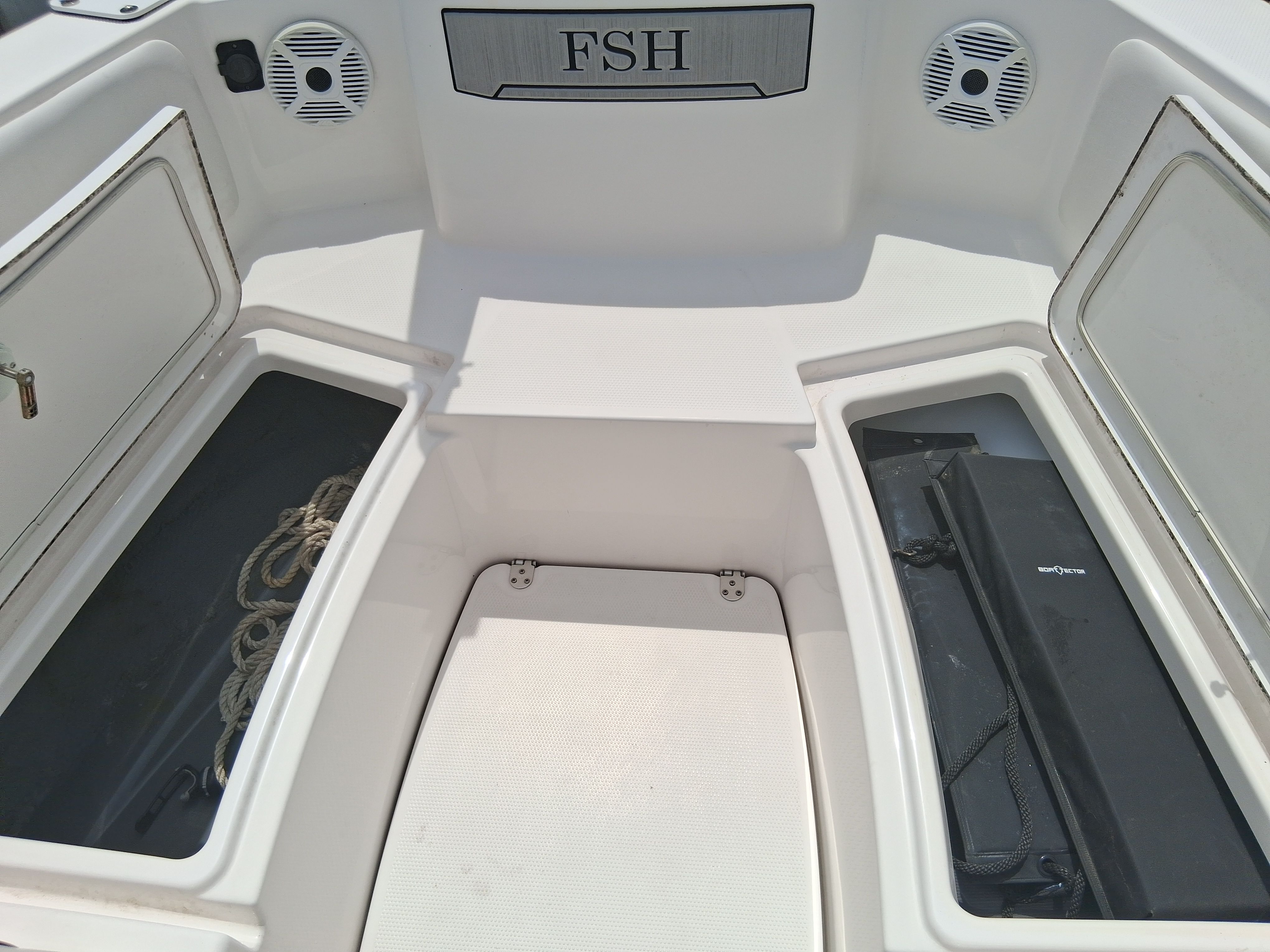 The image shows the bow of a Yamaha 220 FSH Sport boat with storage compartments and speakers.