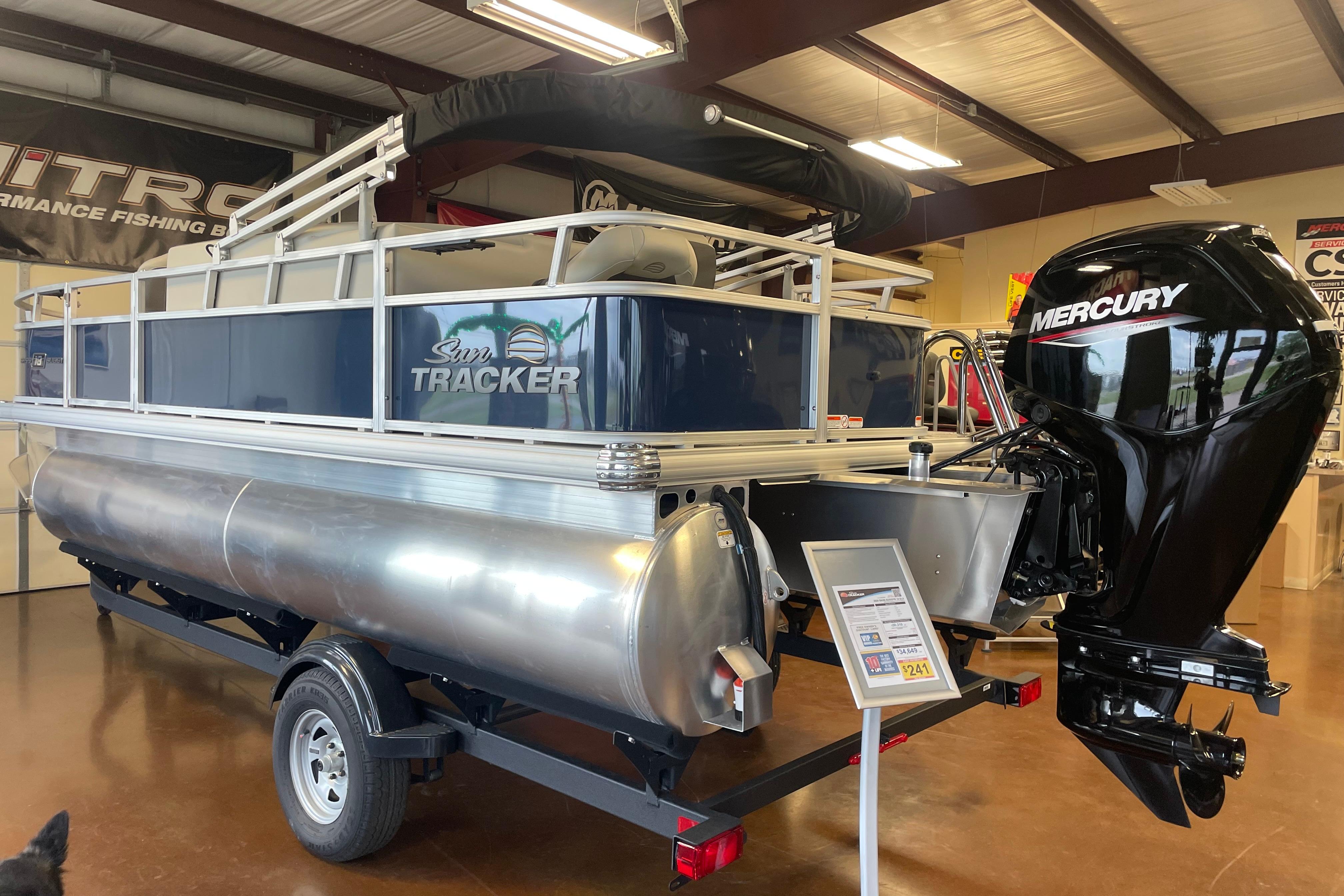 2026 Sun Tracker Bass Buggy 18 DLX pontoon boat with Mercury outboard motor in showroom.