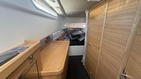 Luxurious interior of 2025 Nimbus T11 boat with wooden cabinetry and cozy sleeping area.