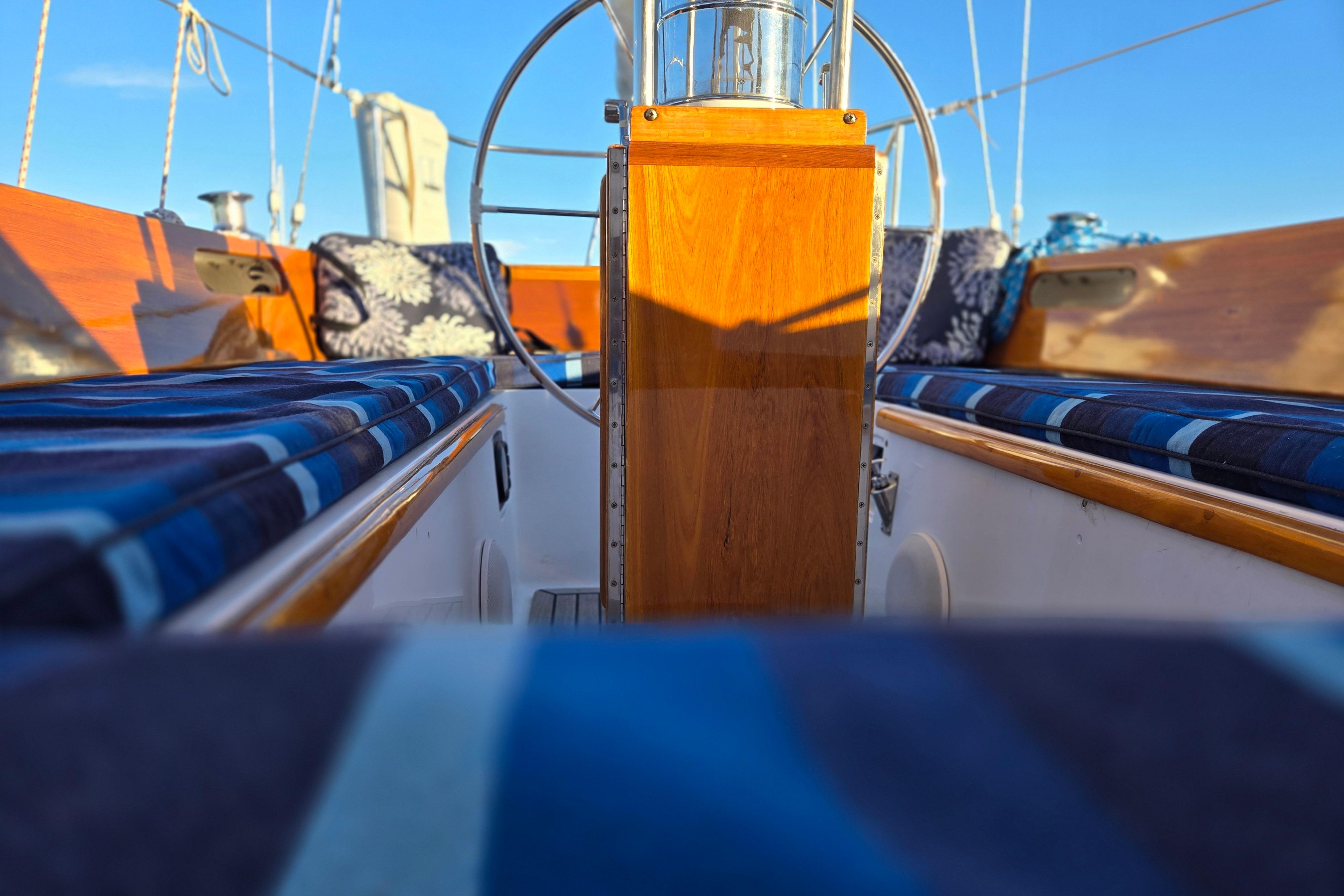 1970 Hinckley Bermuda 40 sailboat cockpit with wooden accents and blue-striped cushions.
