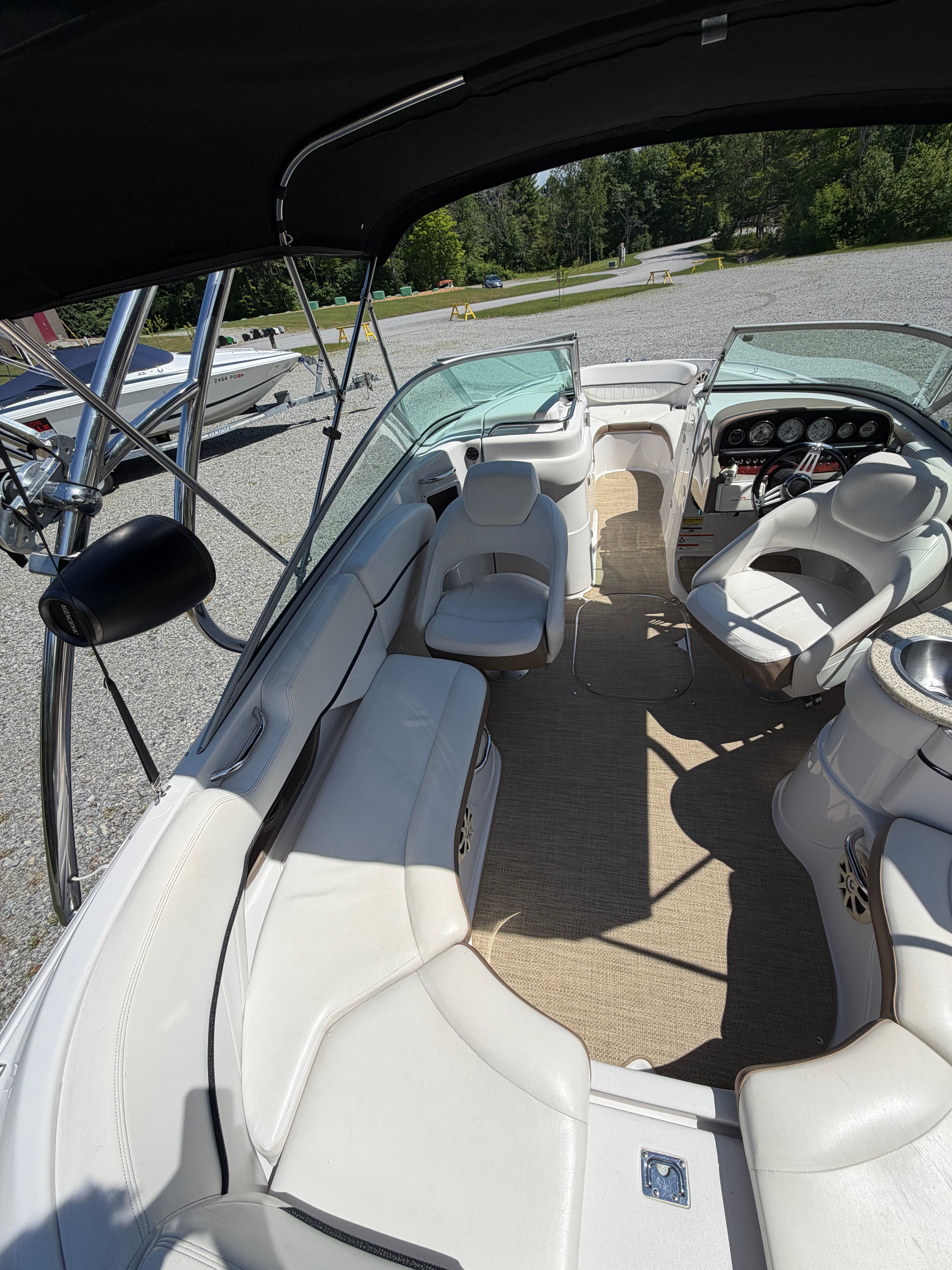 Interior view of a 2008 Four Winns H240 Frenzy with white seating and a black canopy.