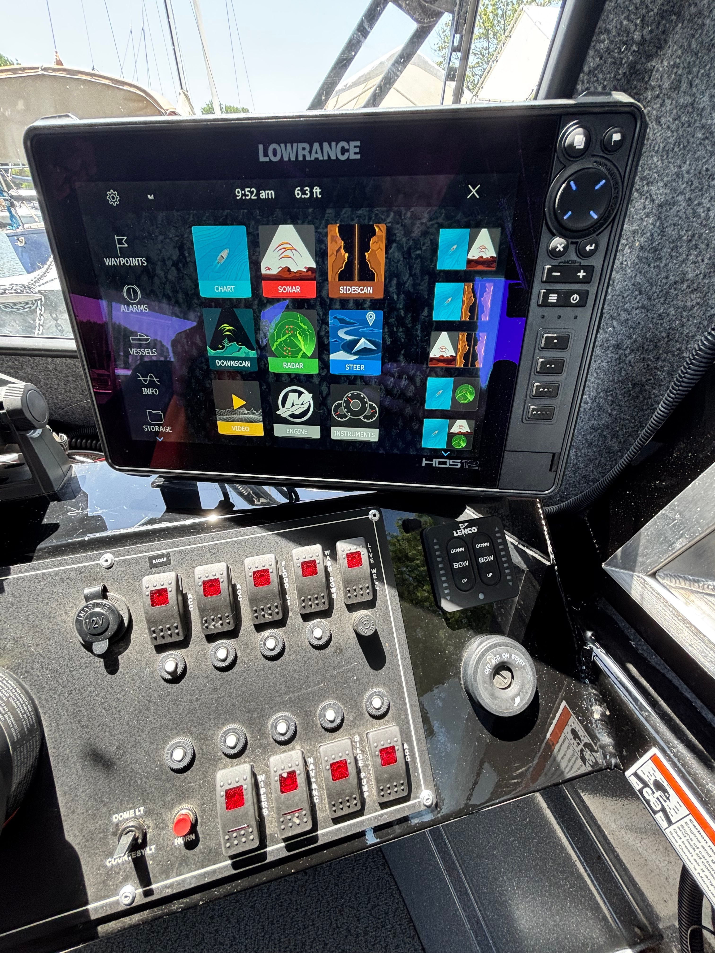 The image shows a boat's helm with a Lowrance navigation system and multiple switches.