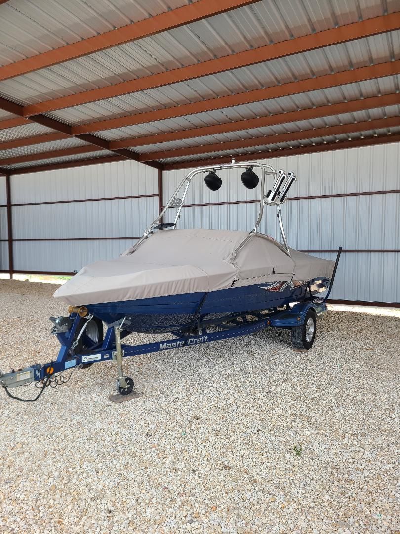 2003 MasterCraft X-9 boat with cover, parked under a metal shelter.