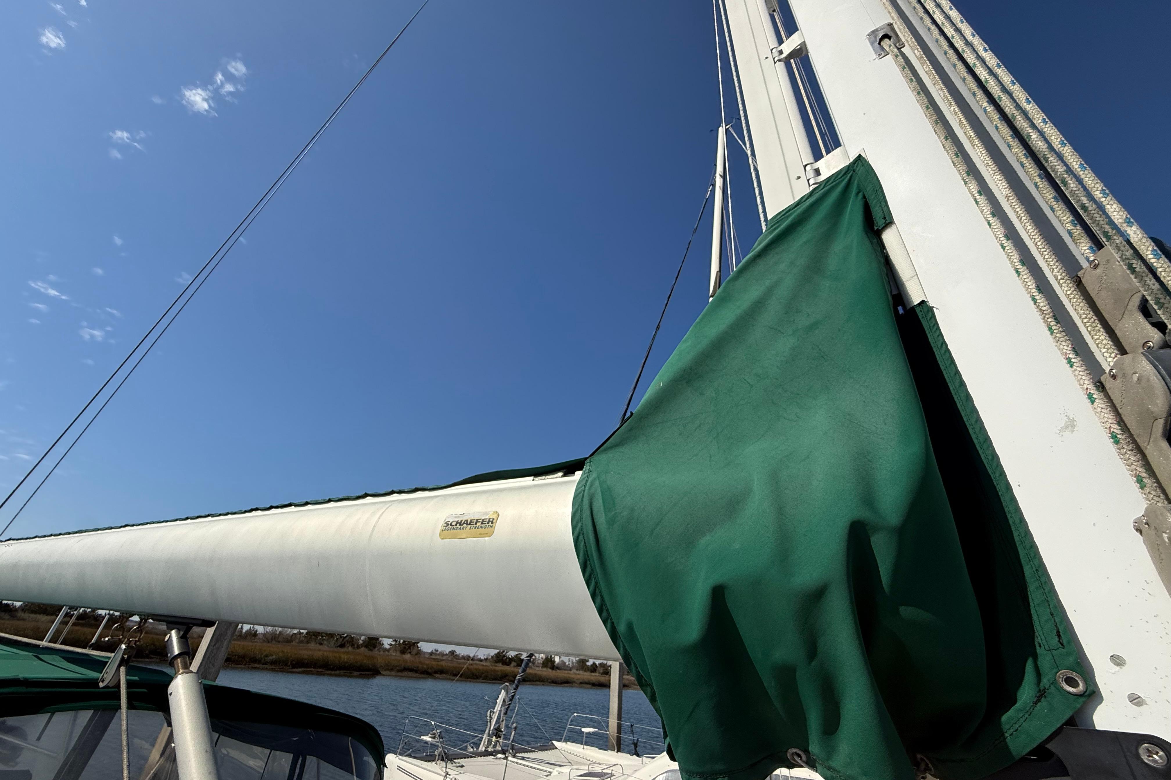 Sailboat mast with green sail cover under clear blue sky, Passport 456, 1999 model.