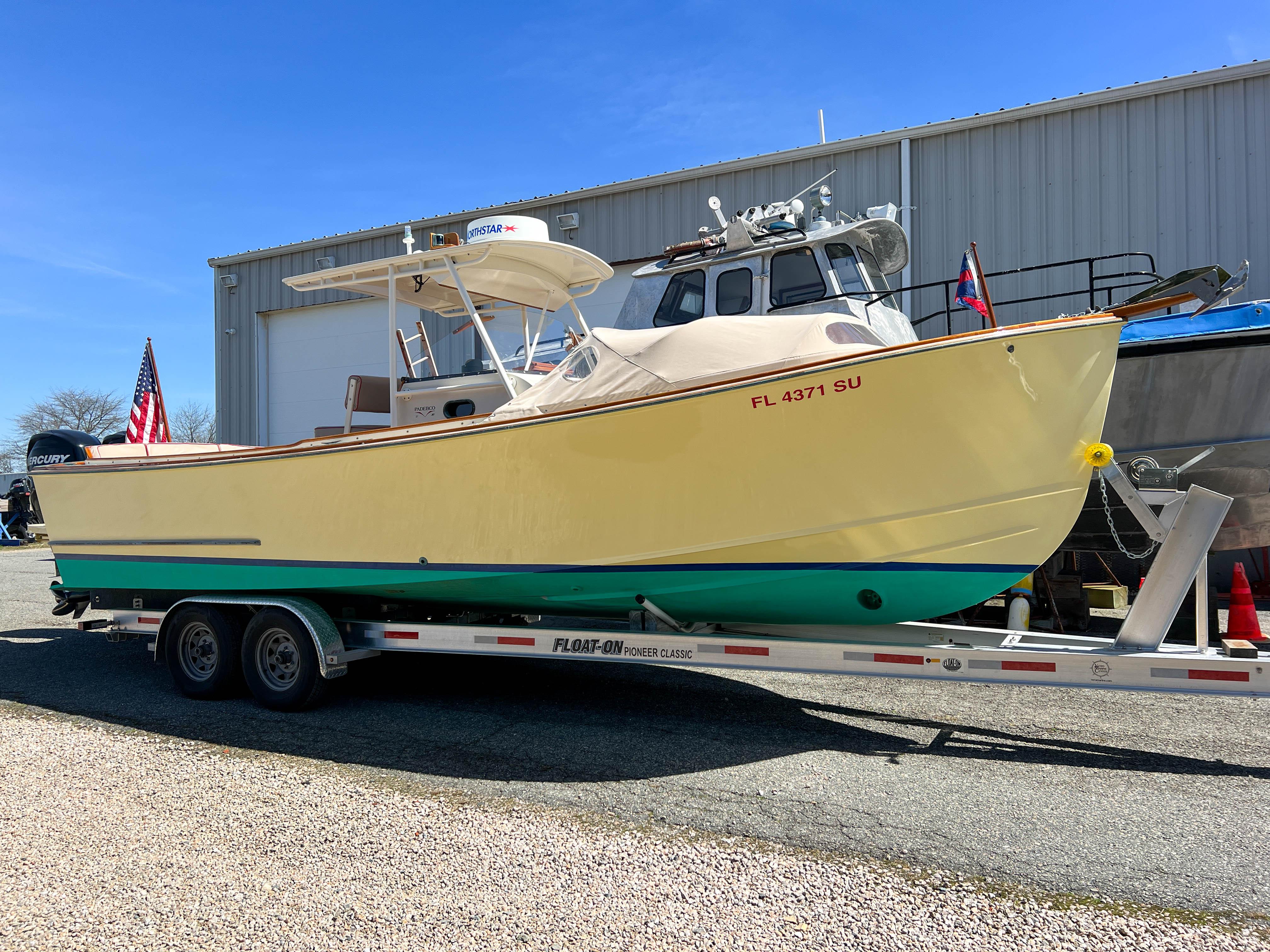 2003 Padebco V27 Center Console boat on trailer, parked outside a warehouse.
