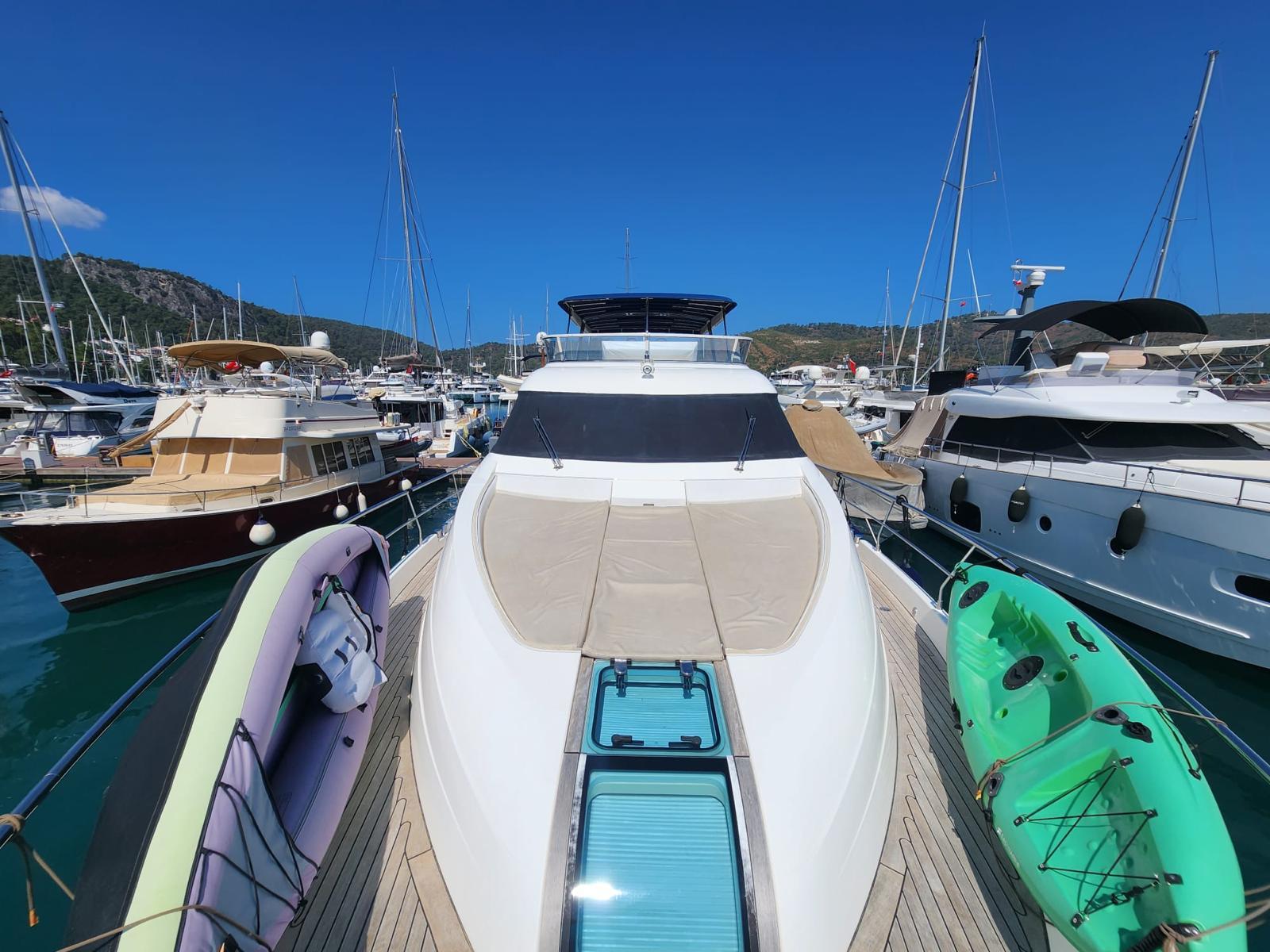 Fairline Squadron 65 yacht, 2012 model, docked in a marina with kayaks and boats nearby.