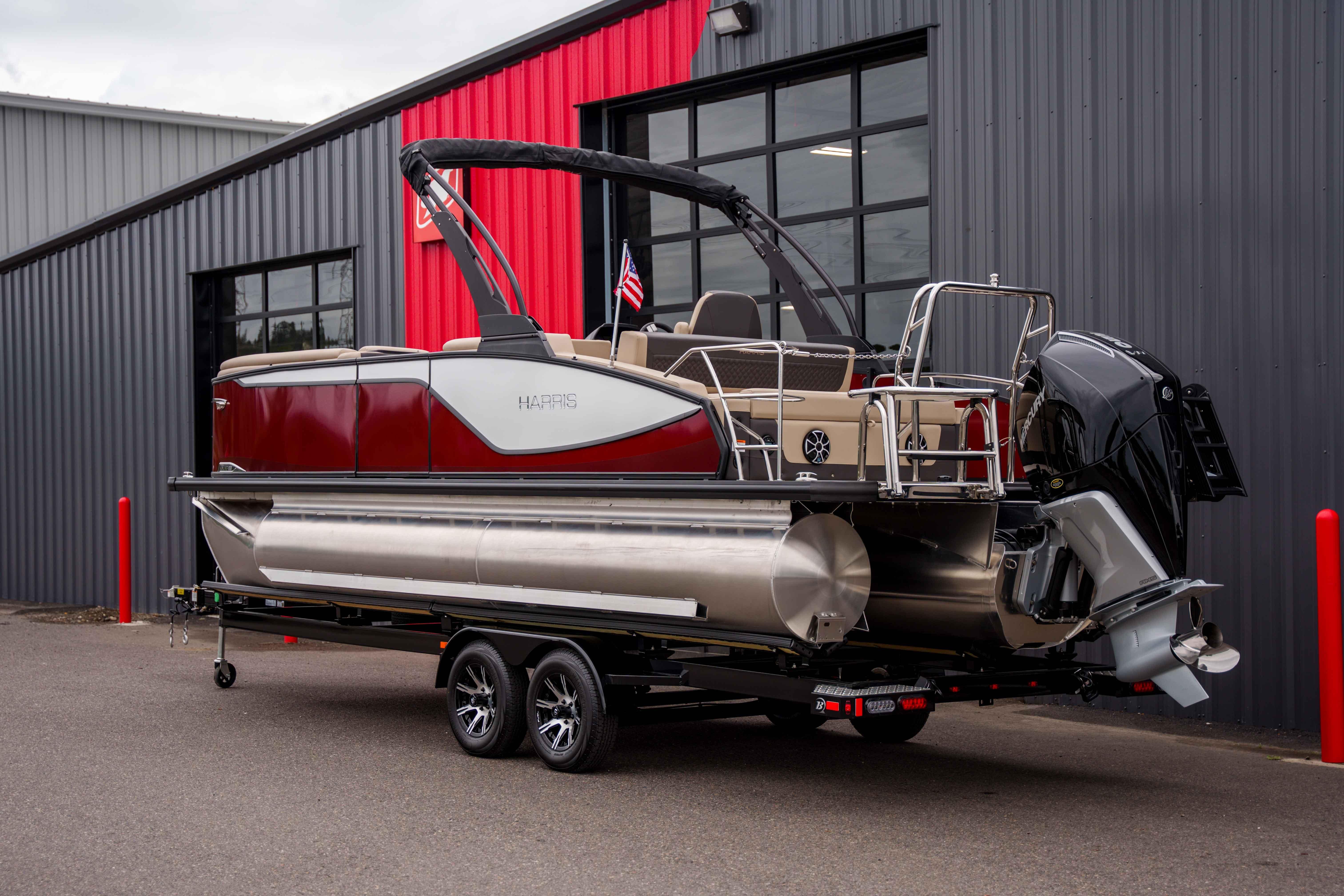 2026 Harris Sunliner 230 pontoon boat on trailer, parked outside a modern building.
