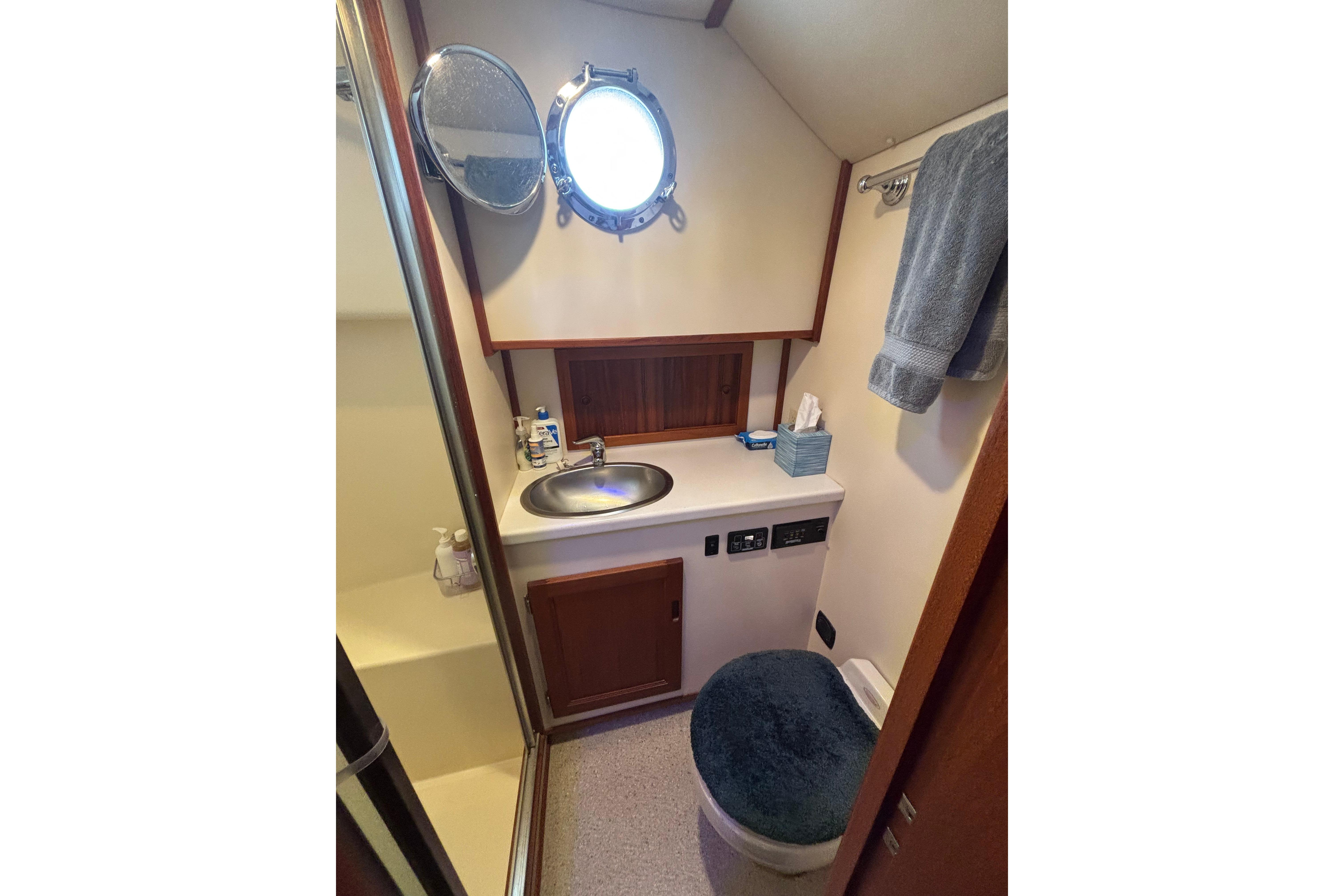 Bathroom interior of 2004 Nordic Tug 37 with sink, mirror, and porthole window.