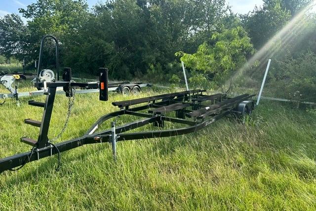 Trailer for 2019 Sun Tracker Party Barge 22 XP3 in grassy field.