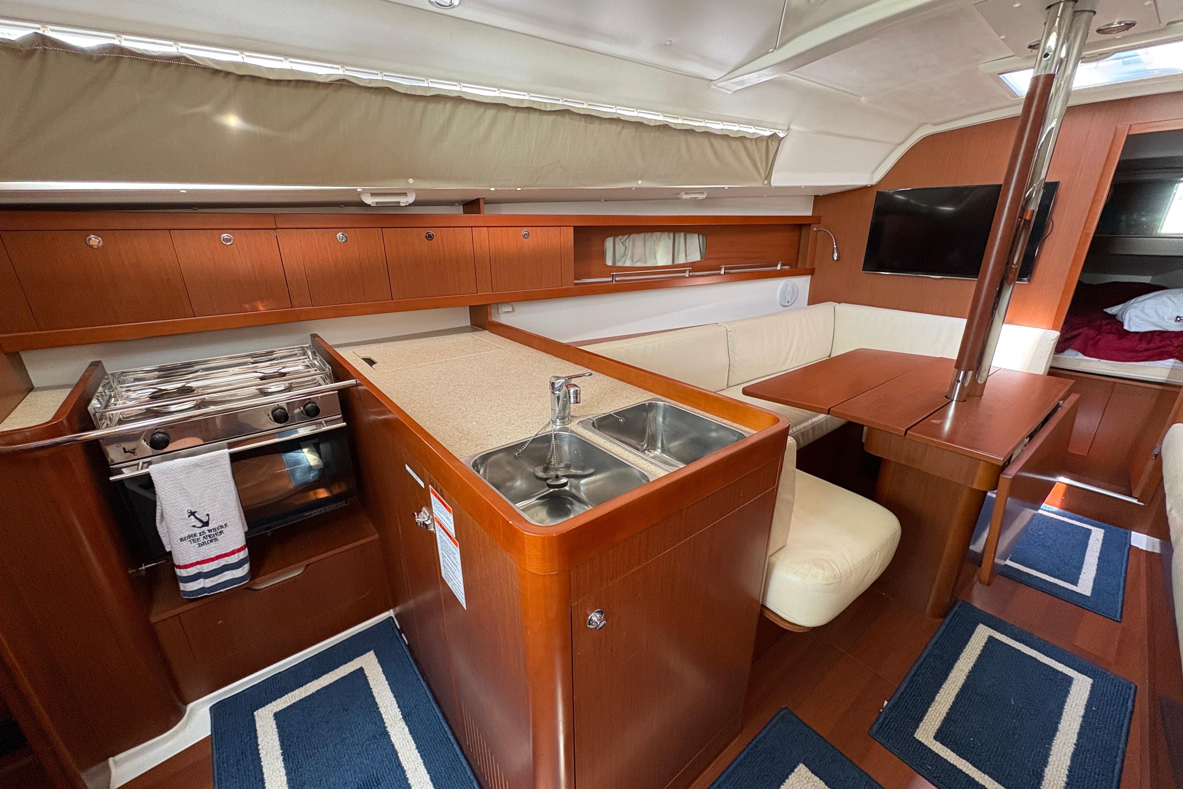 Interior of 2015 Beneteau Oceanis 34 yacht with kitchen, dining area, and wood finish.
