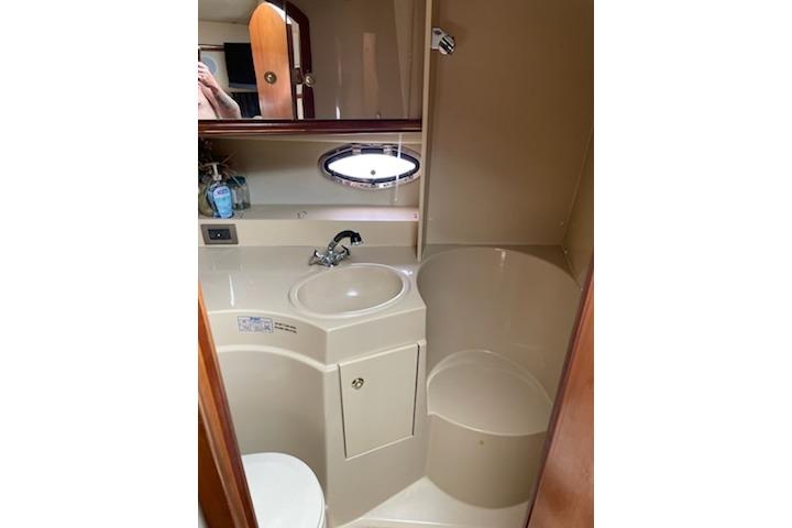 Bathroom interior of 2002 Cruisers Yachts 3372 Express with sink, mirror, and porthole.