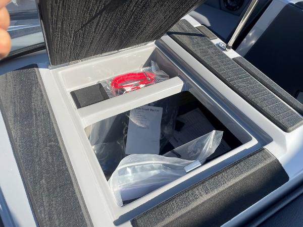 Storage compartment in a 2025 Moomba Mondo boat, containing safety equipment and documents.