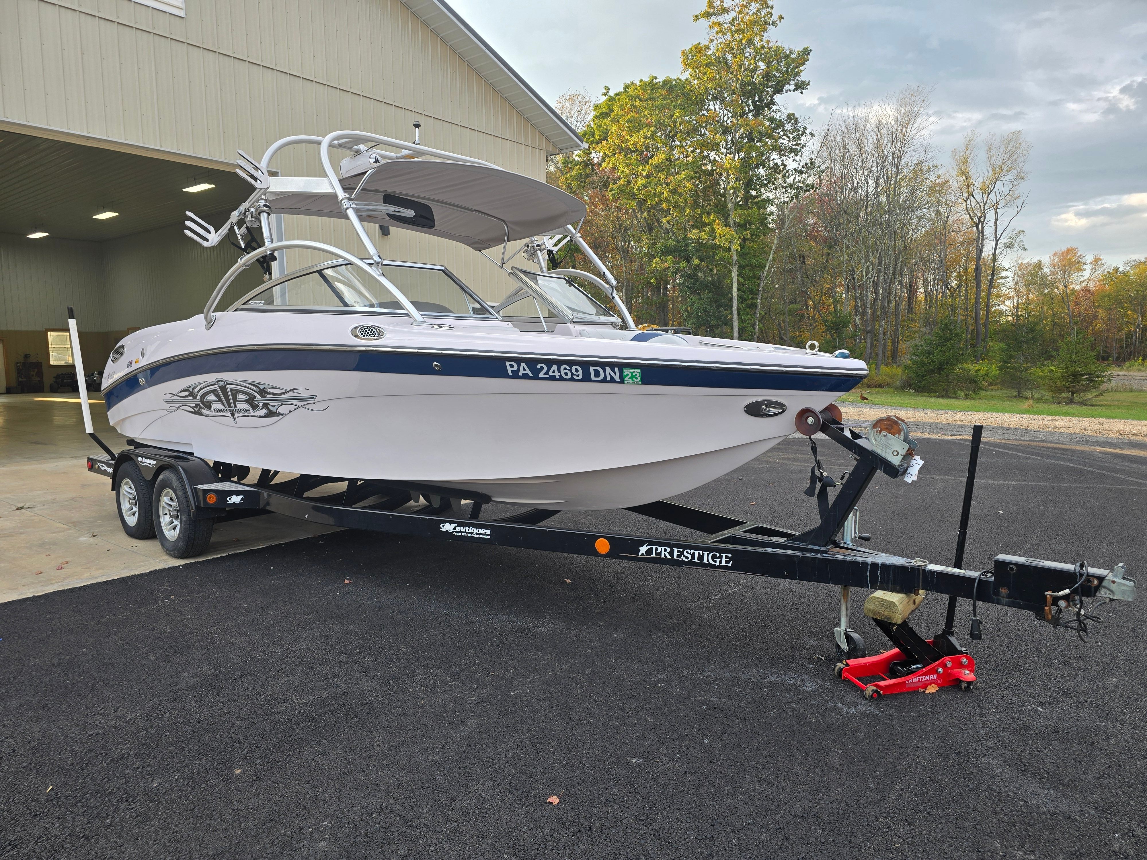 2006 Correct Craft 228 boat on trailer outside garage.