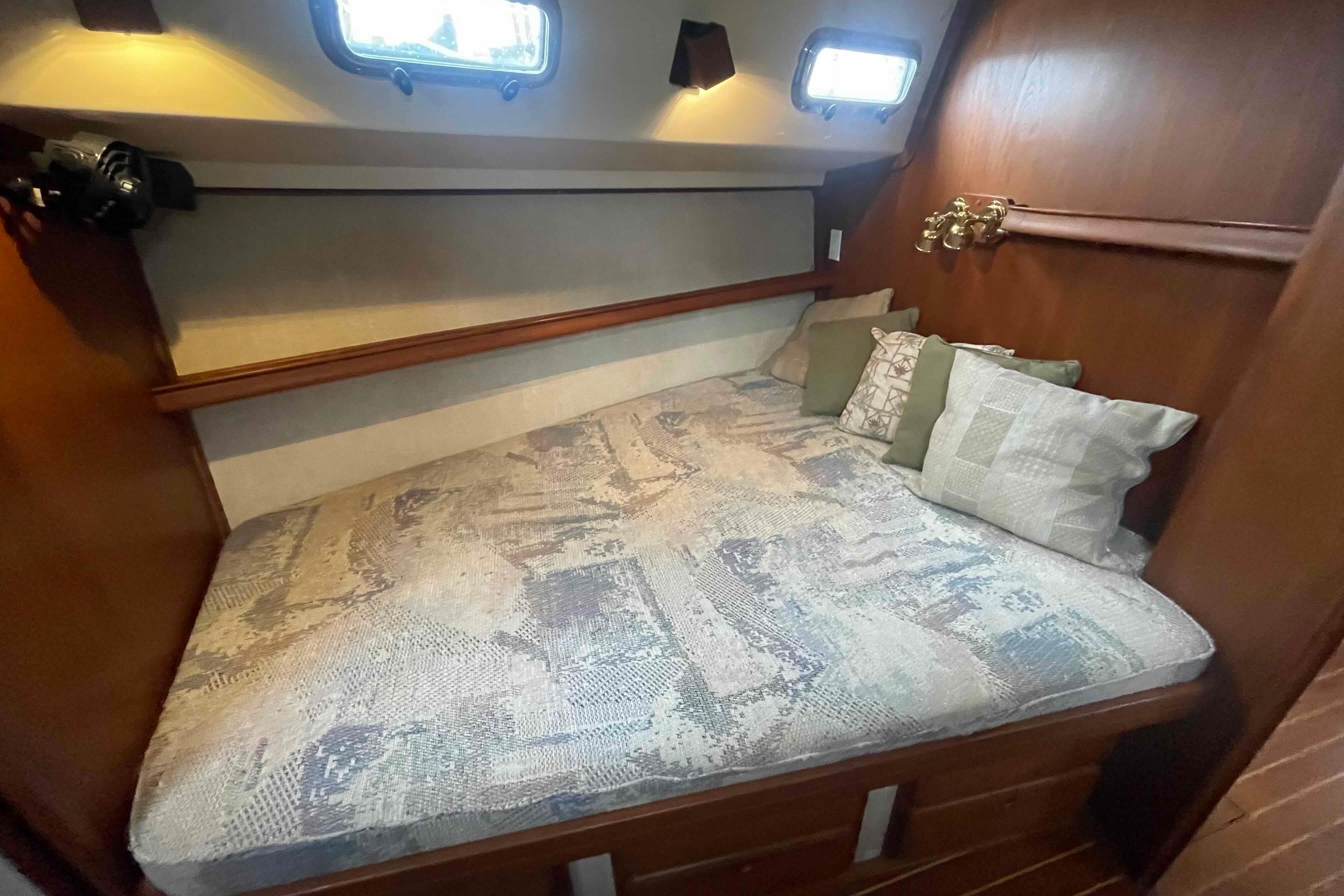 Cozy cabin interior of 1998 Island Packet 40 sailboat with cushioned bed and pillows.