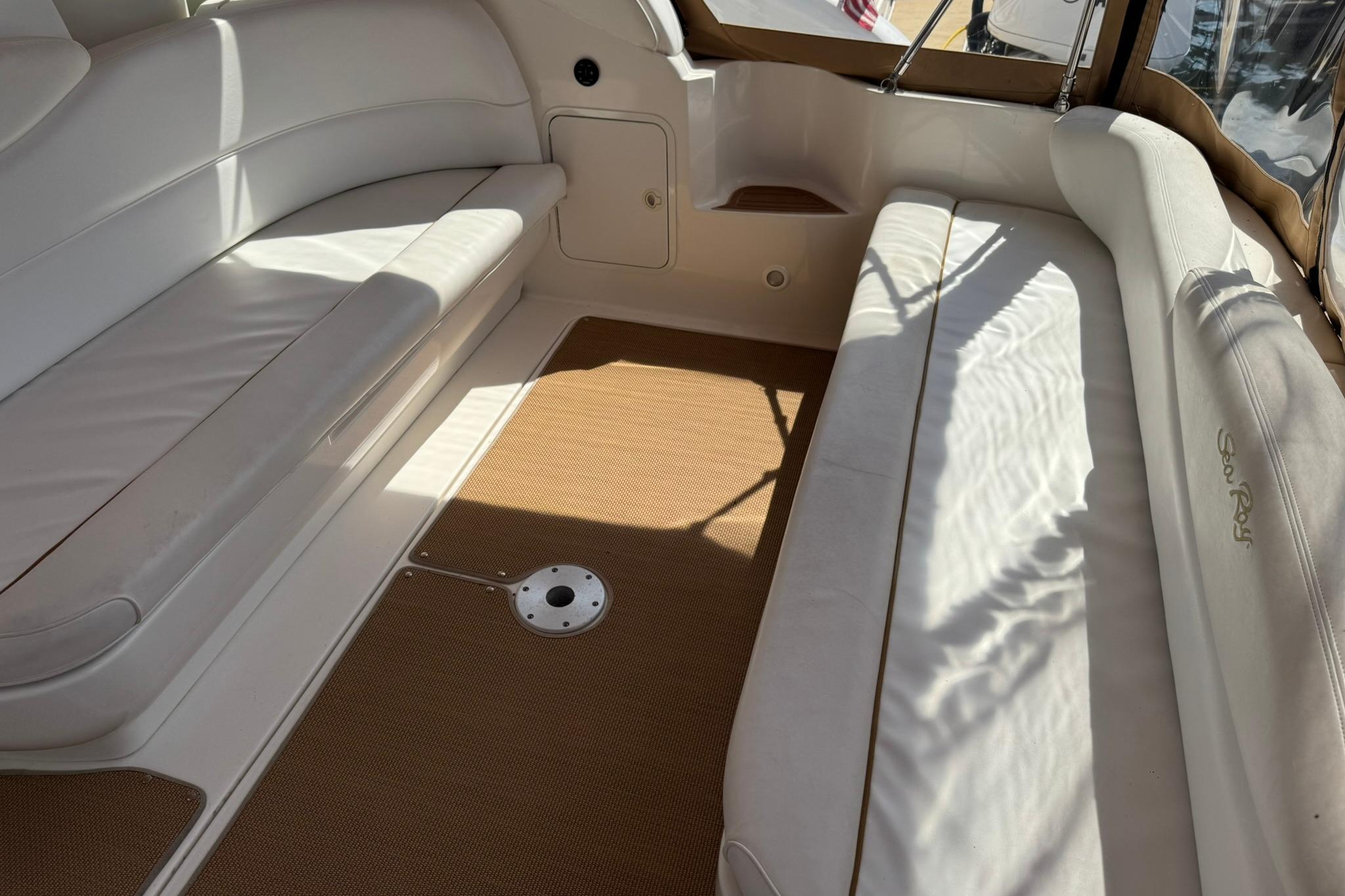 Interior of a 2001 Sea Ray 340 Sundancer boat with white seating and brown flooring.