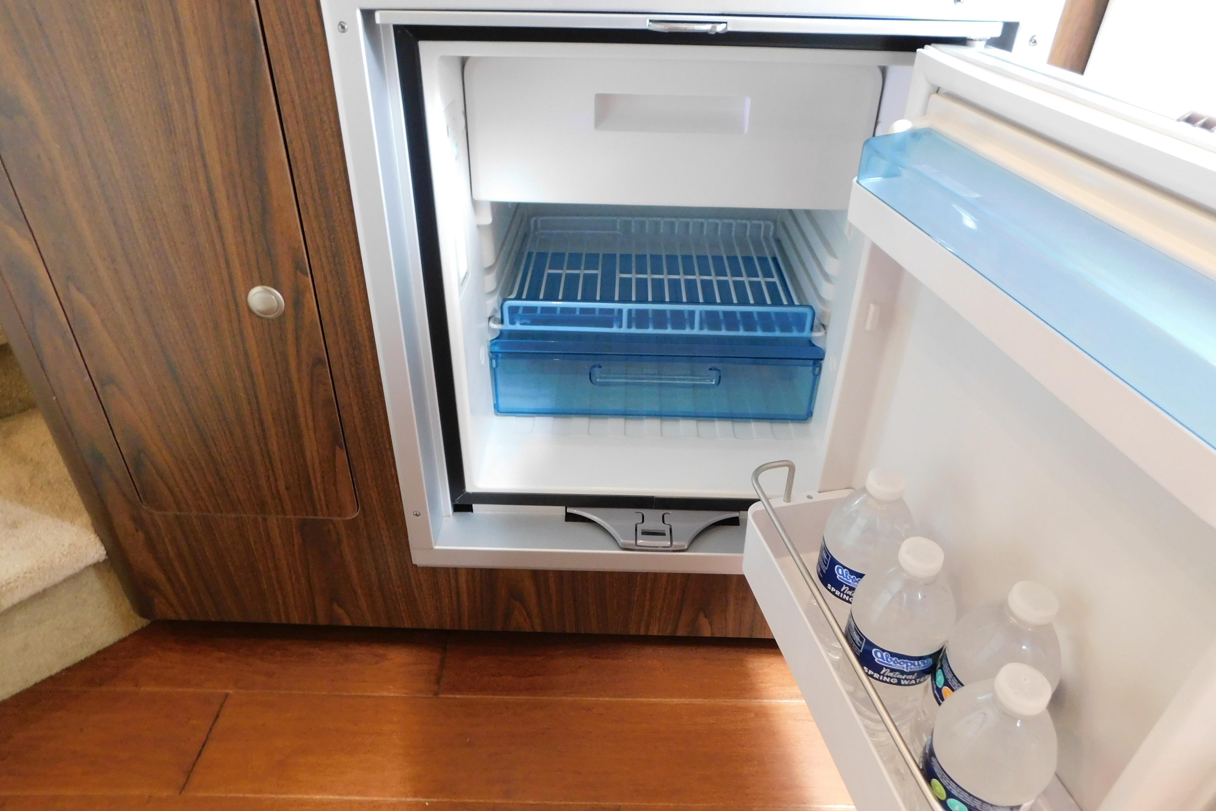 Open refrigerator in 2017 Rinker EX 320 boat, showing interior shelves and bottled water.
